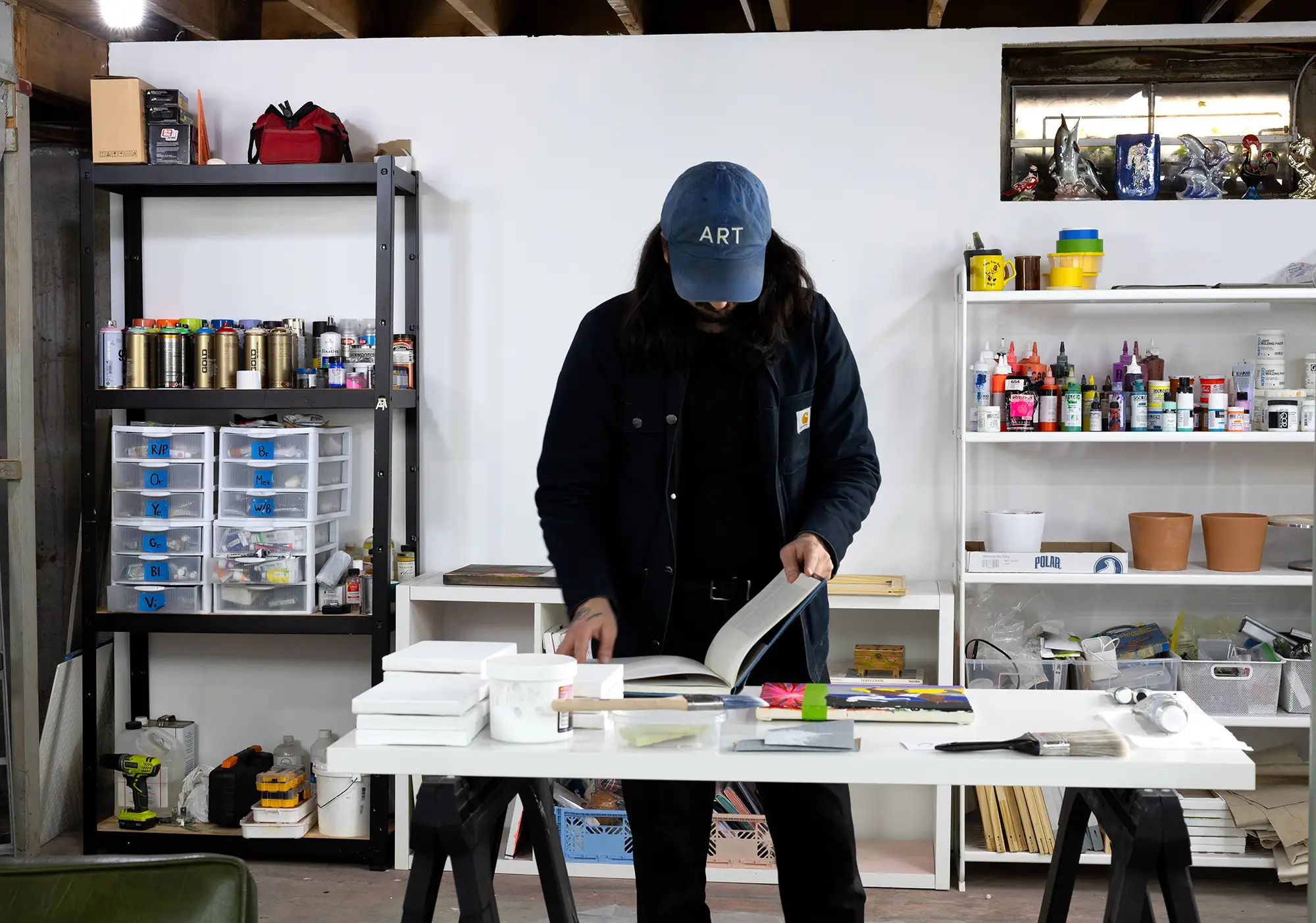 Brandon aguiar, promising young contemporary painter in his studio looking to art books