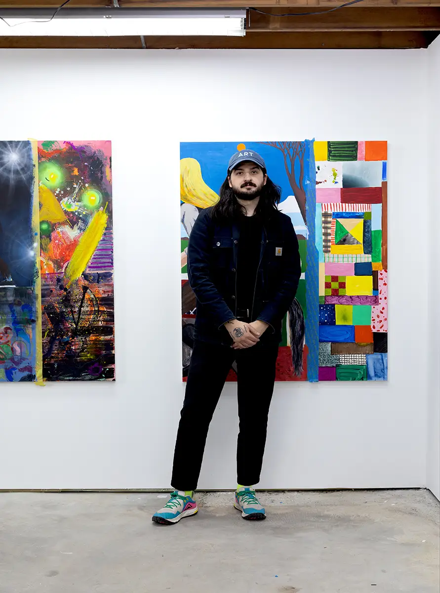 brandon aguiar, between two of his paintings in his studio, emerging art now