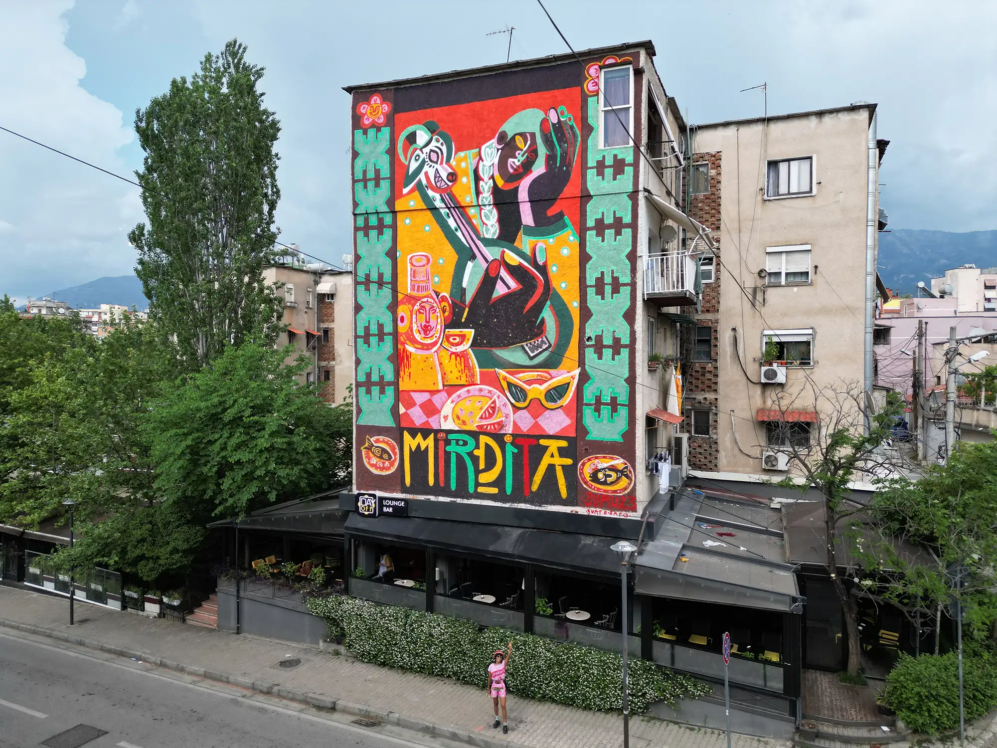 mural festival tirana, the artist jumu monster in front of a great wall piece contemporary art