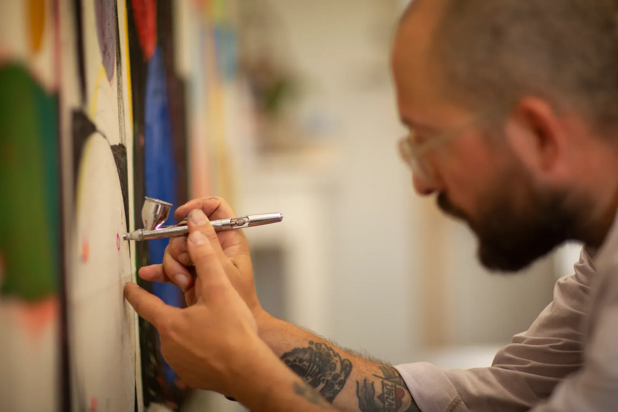 sune christiansen applying fine details to abstract painting with airbrush in studio