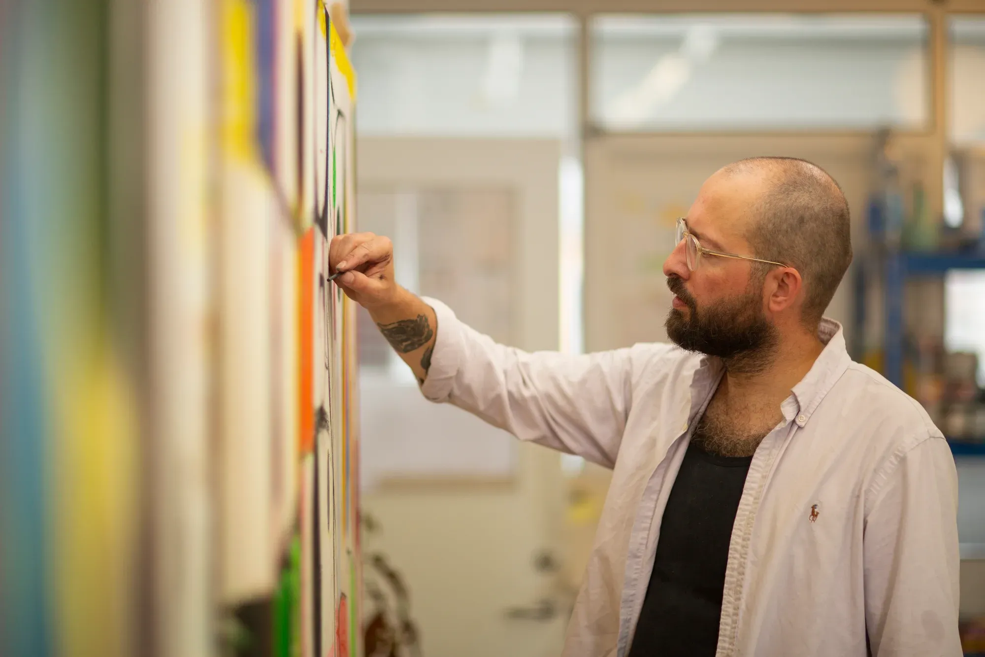sune christiansen applying fine details to abstract painting with airbrush in studio contemporary art colorful