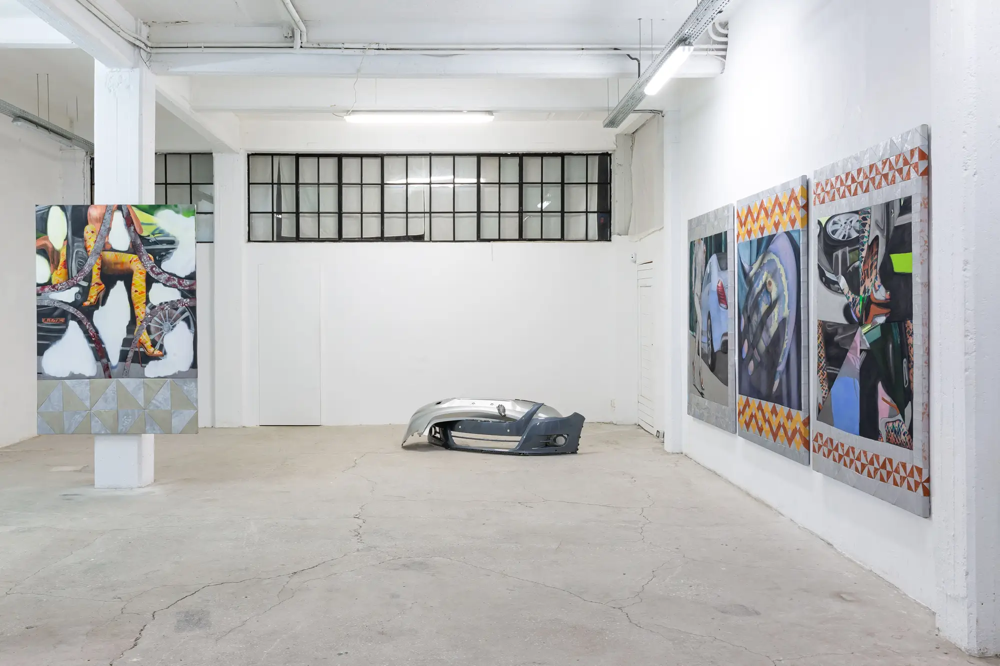 Exhibition view with sculptural objects and painted car components in a minimal gallery setting, solo show by Bety Krňanská