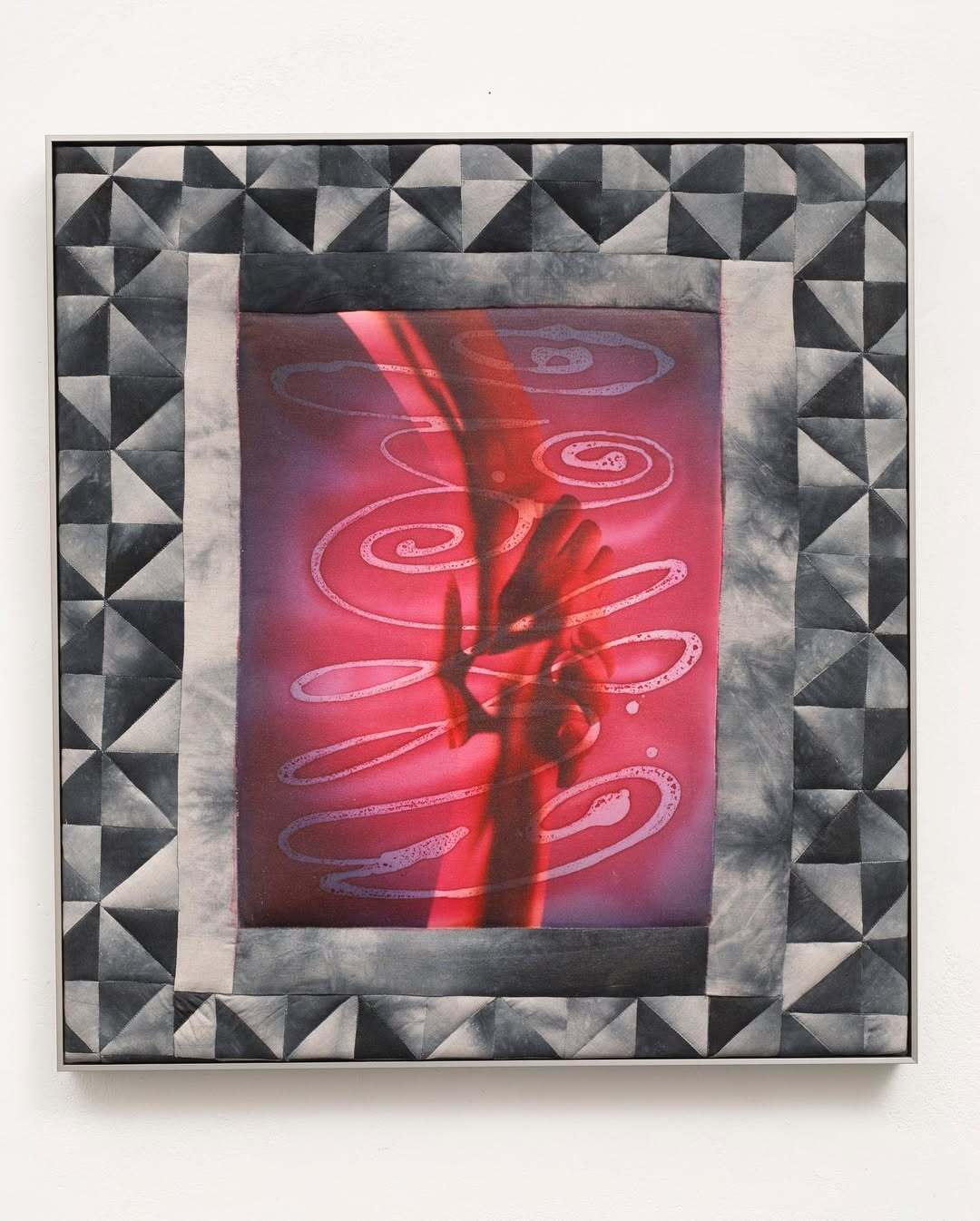 Framed painting by Bety Krňanská titled 'Better Together,' showing two hands in silhouette over a red background with swirling white motifs, bordered by a geometric quilted black-and-white textile frame