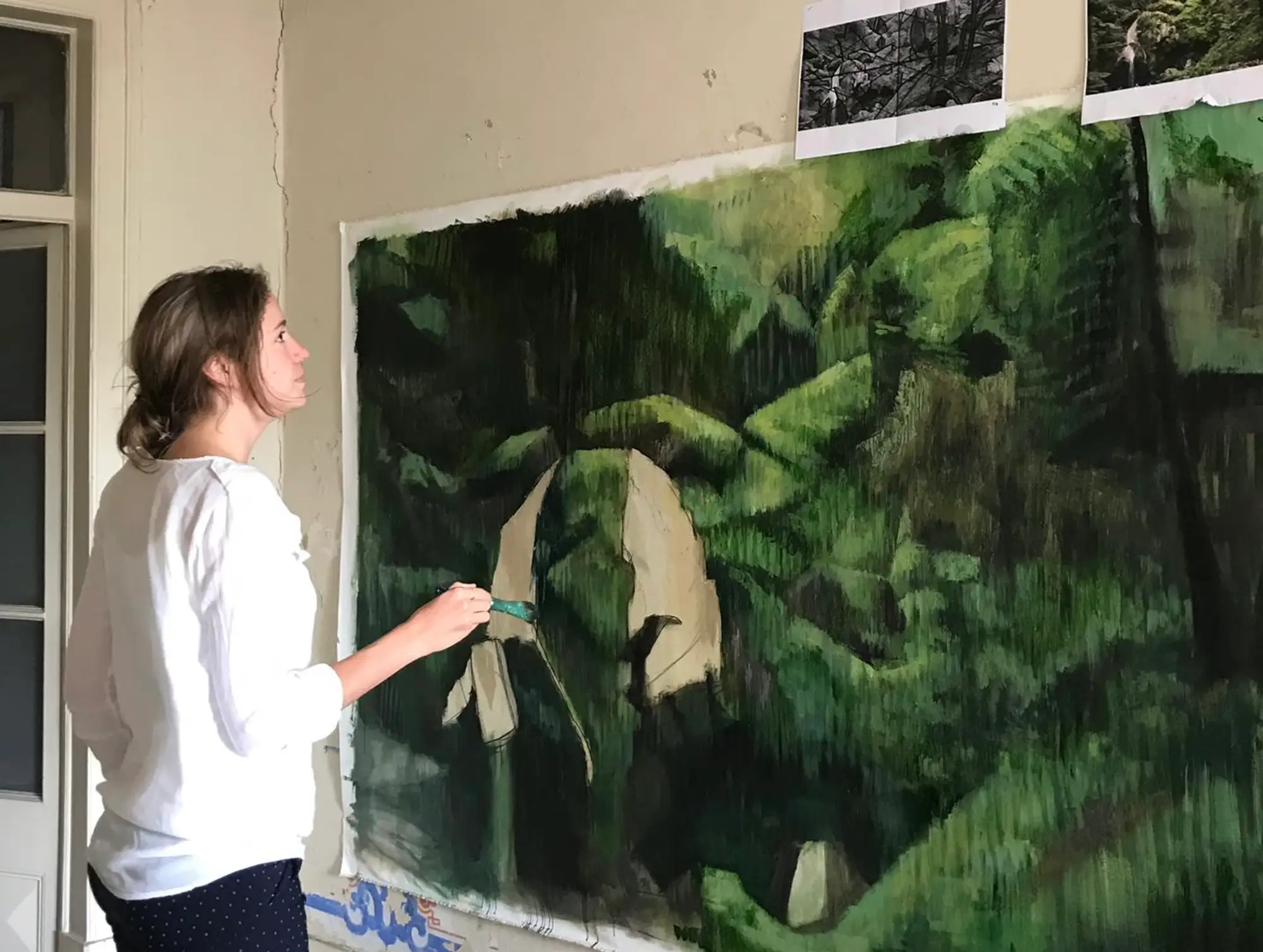 View of Stefanie Pullin standing in front of her large jungle-like canvas