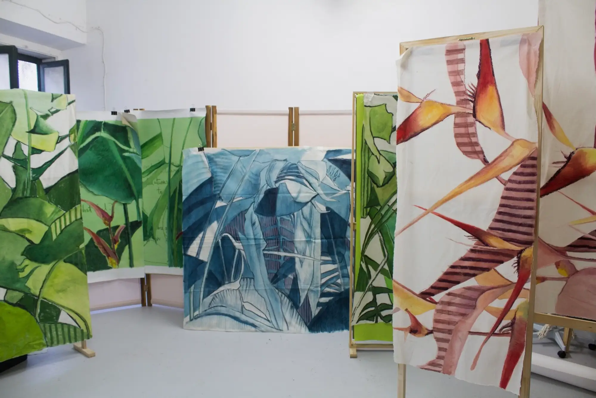 Stefanie Pullin painting in her Lisbon studio surrounded by green-toned canvases