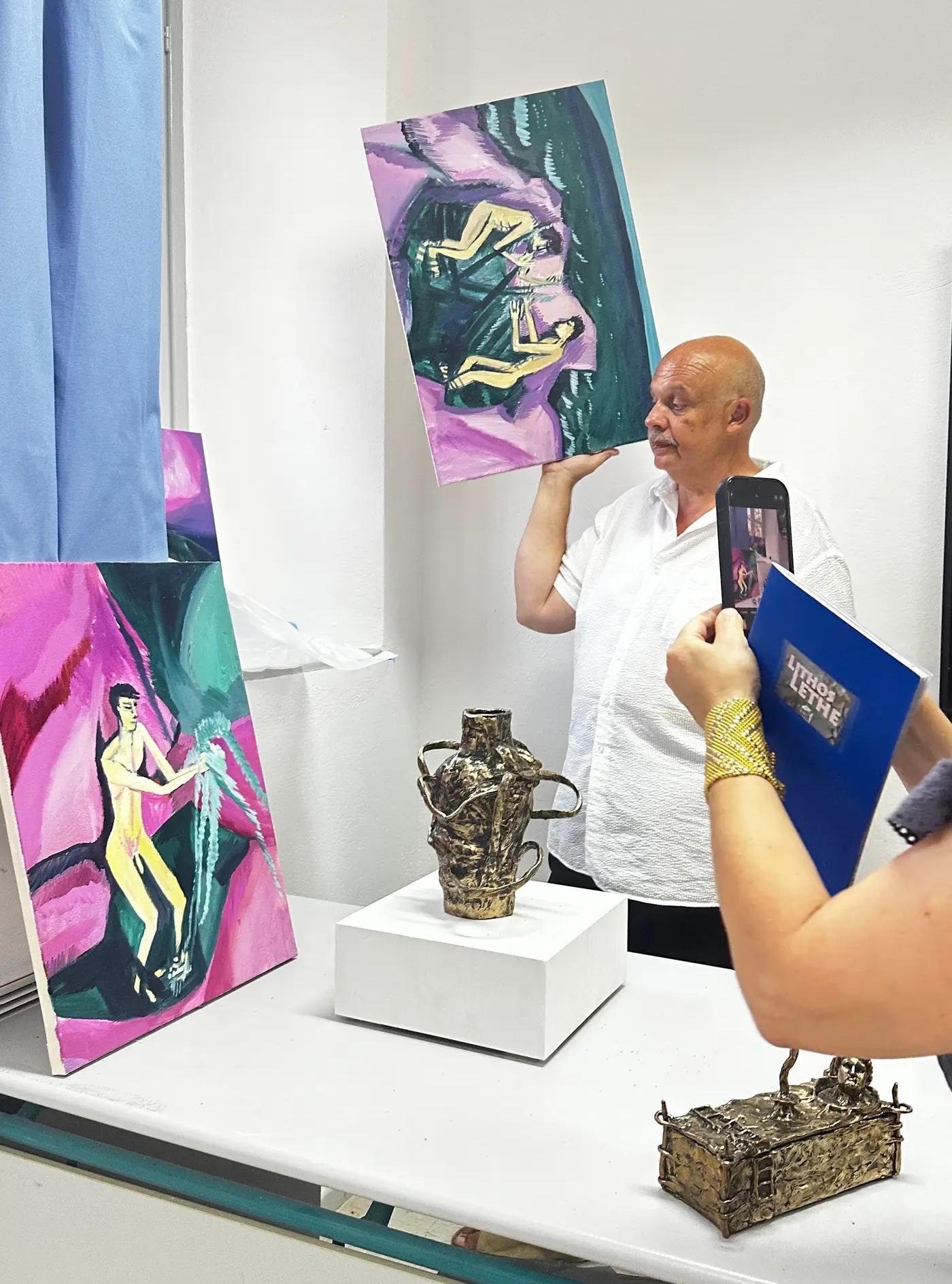 Curator Dimitrios Antonitsis presenting Konrad Zukowski’s paintings alongside bronze sculptures by William Farrell during Hydra School Projects 2025, photographed by Munchies Art Club.