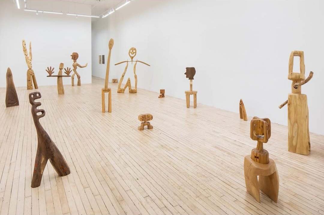 Installation view of Hunter Potter’s wooden sculptures from “The Pasture” at SHRINE Gallery, New York City, featuring carved human-like forms in varying scales across a light wood floor.