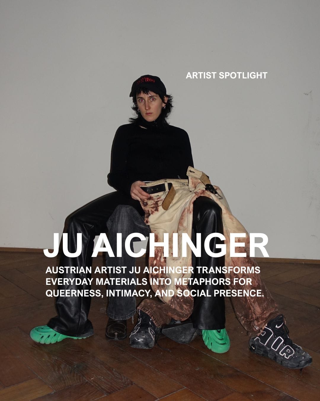Portrait of Austrian artist Ju Aichinger, seated in a minimalist space wearing black and green footwear, holding fabric and sculptural materials. Aichinger, known for transforming everyday objects into conceptual works exploring queerness, intimacy, and social presence, will present an Artist Statement at Parallel Vienna 2025, a leading alternative art fair showcasing emerging and contemporary talents.
