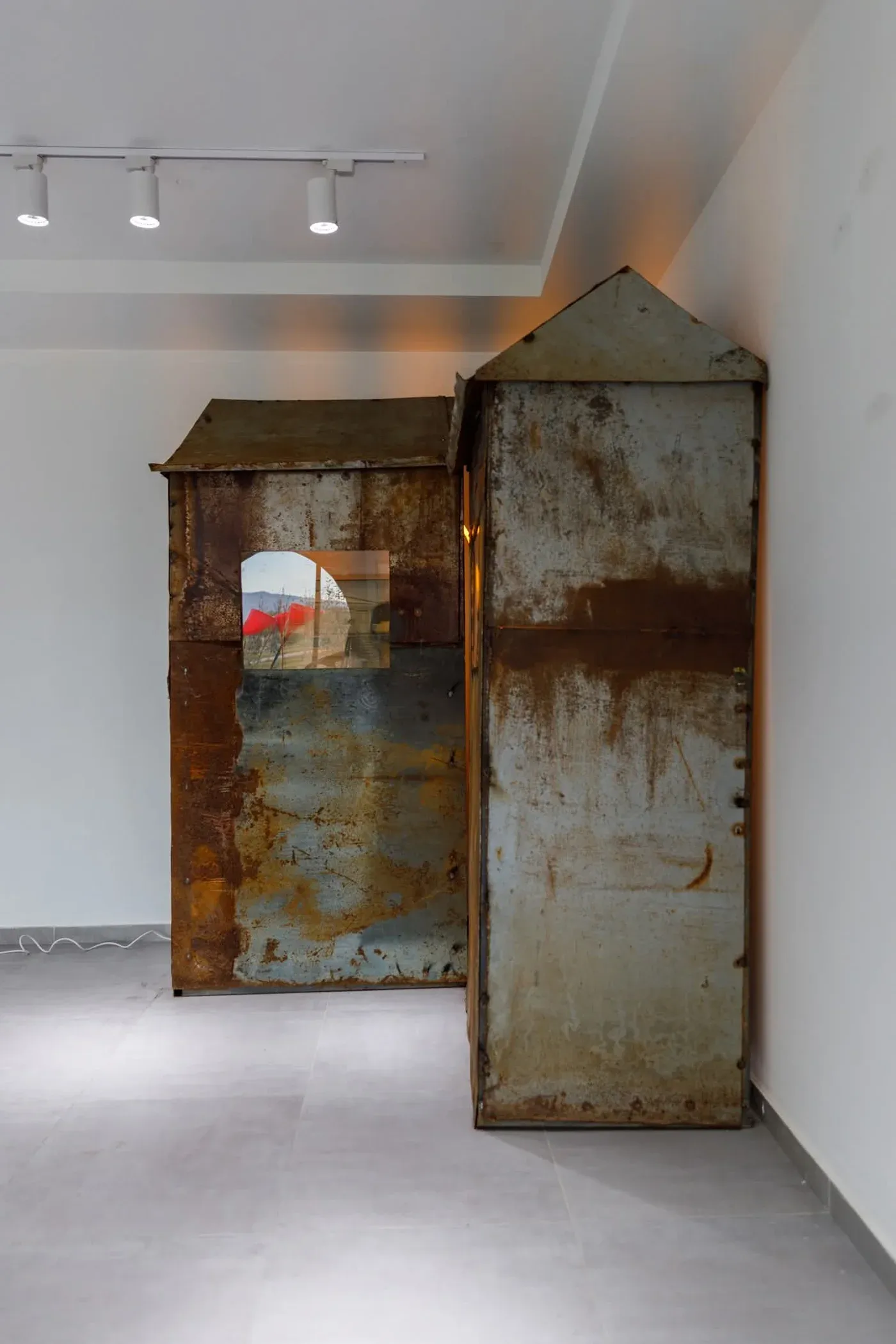 Mariam Akubardia, “River of Rust-Coloured Tears.” Side view of rusted hut installation with glowing interior.