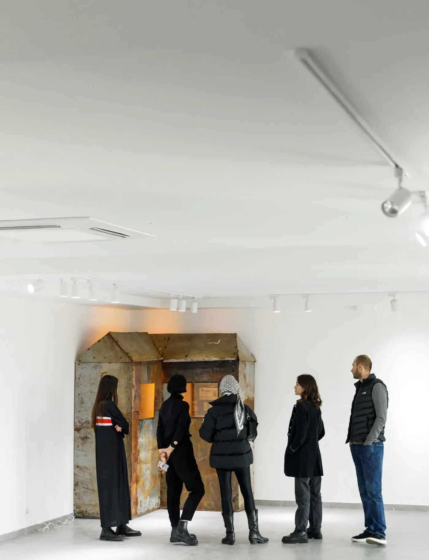 Mariam Akubardia, “River of Rust-Coloured Tears.” Group of visitors viewing rusted hut installation.