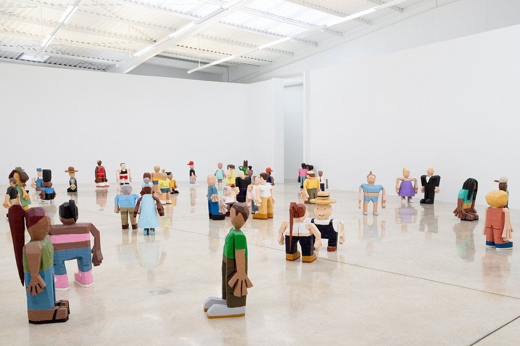 hunter potter exhibition at l21 gallery Spain a room filled with colorful short wooden sculptures of people.