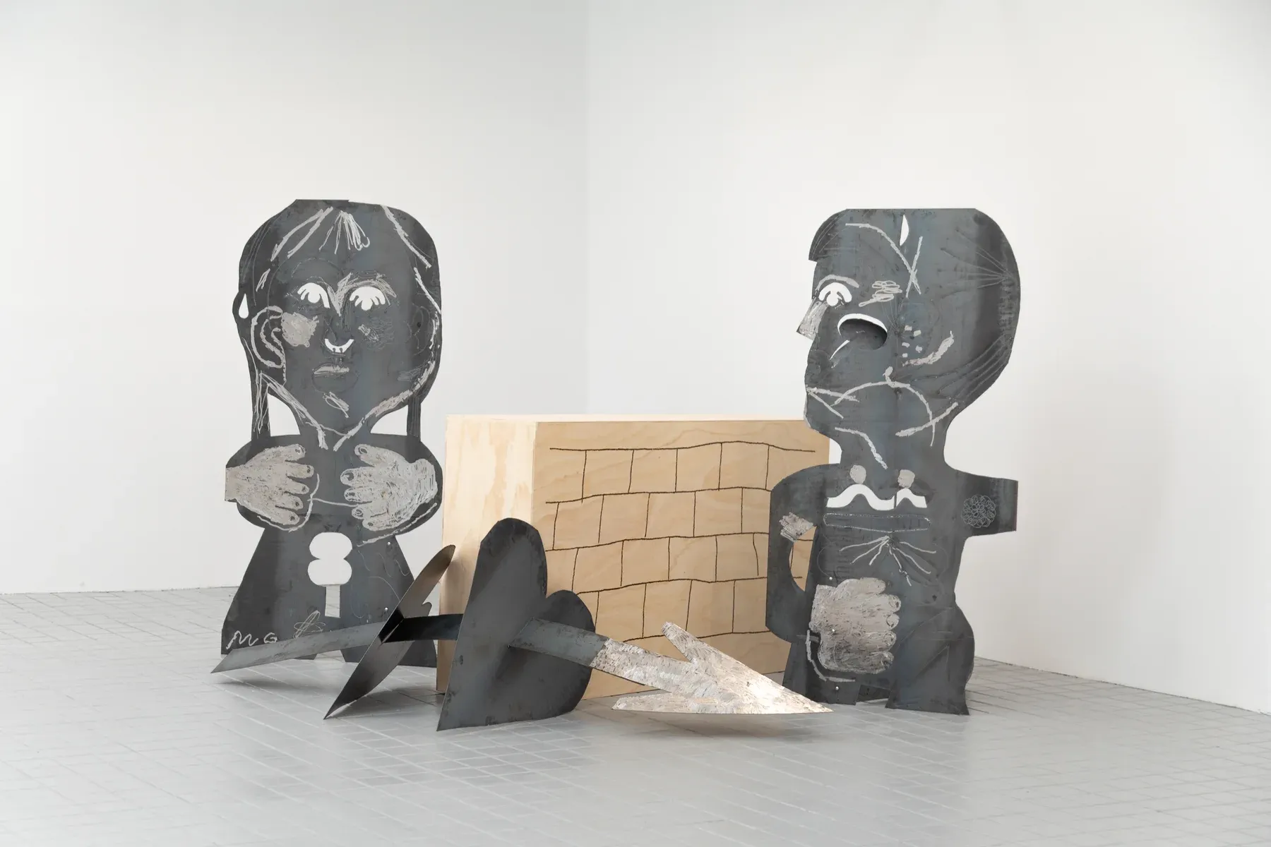 Steel and wood sculpture installation by Manuel García Fernández featuring figurative cutouts and a heart pierced by an arrow. Exhibited at Marc Bibiloni Gallery, Madrid,