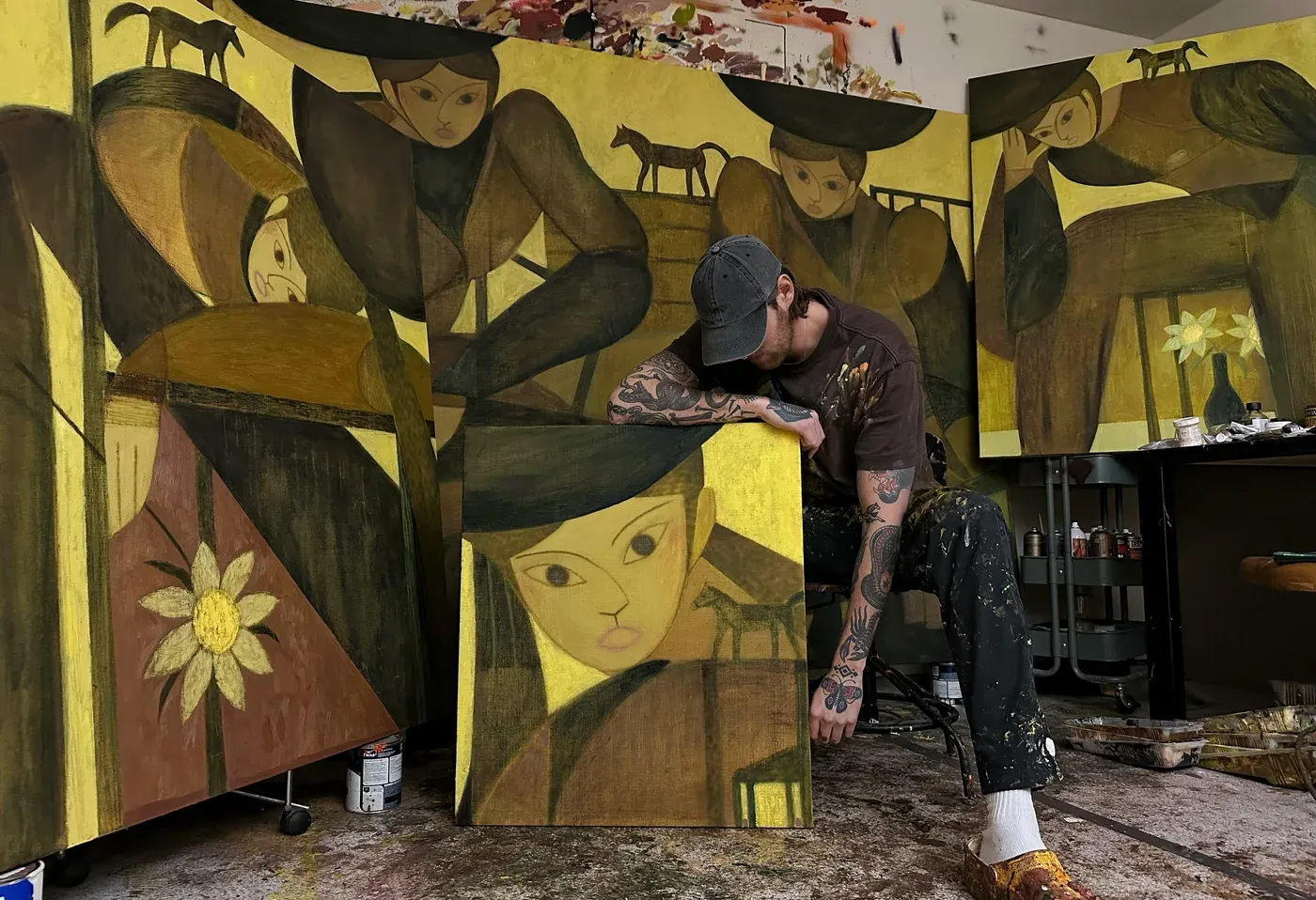 Bob Geerts ( artist feature Catapult - The new munchies art club - Friday dispatch exhibitions)  in his studio, surrounded by new figurative paintings in warm ochre and green tones, image courtesy of the artist and Bruna Collectables