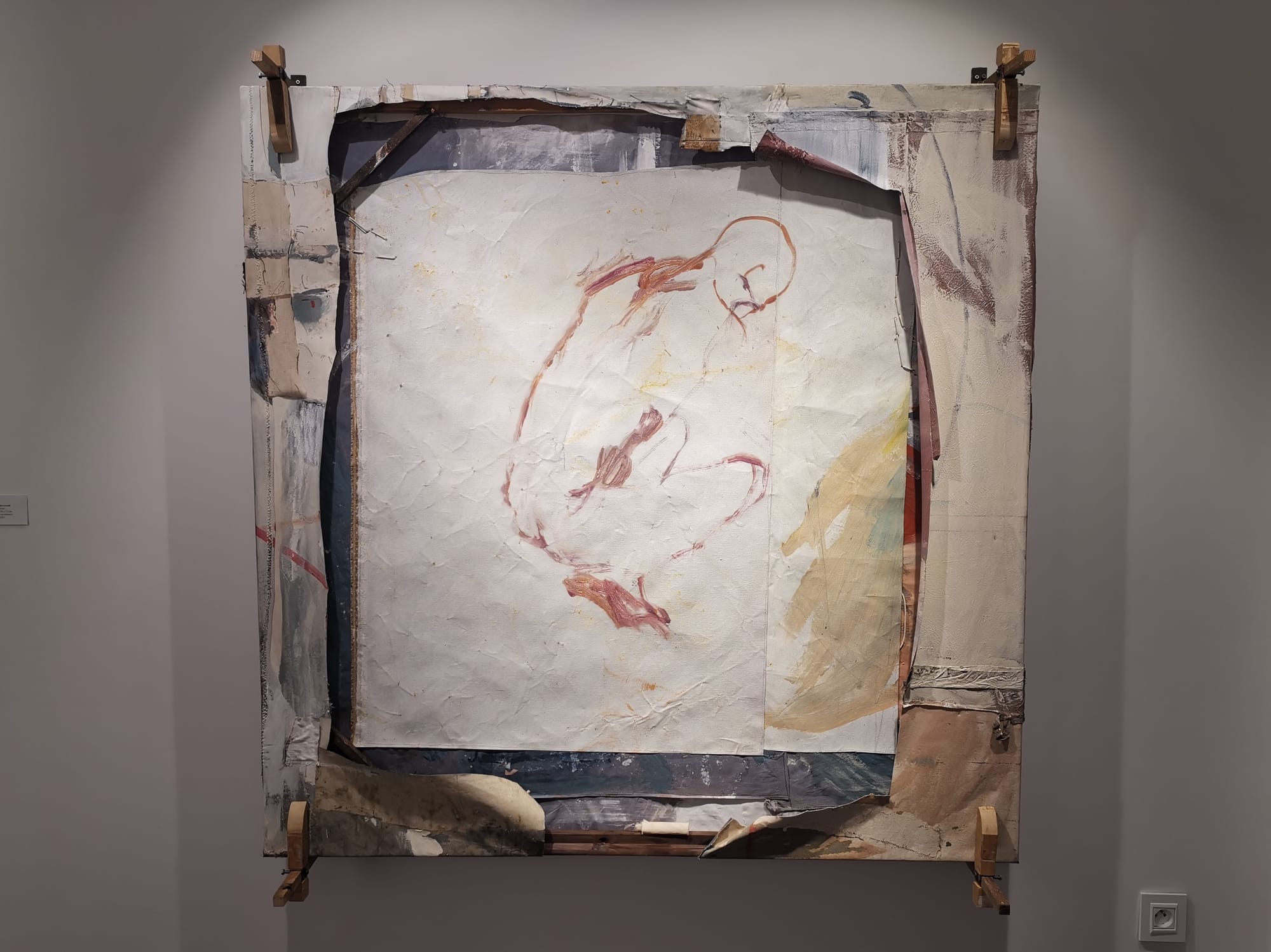 Ruth Devriendt’s 2025 work Brother, a large square canvas with layered surfaces and a central painted figure, shown mounted on the wall. Image courtesy of the artist.