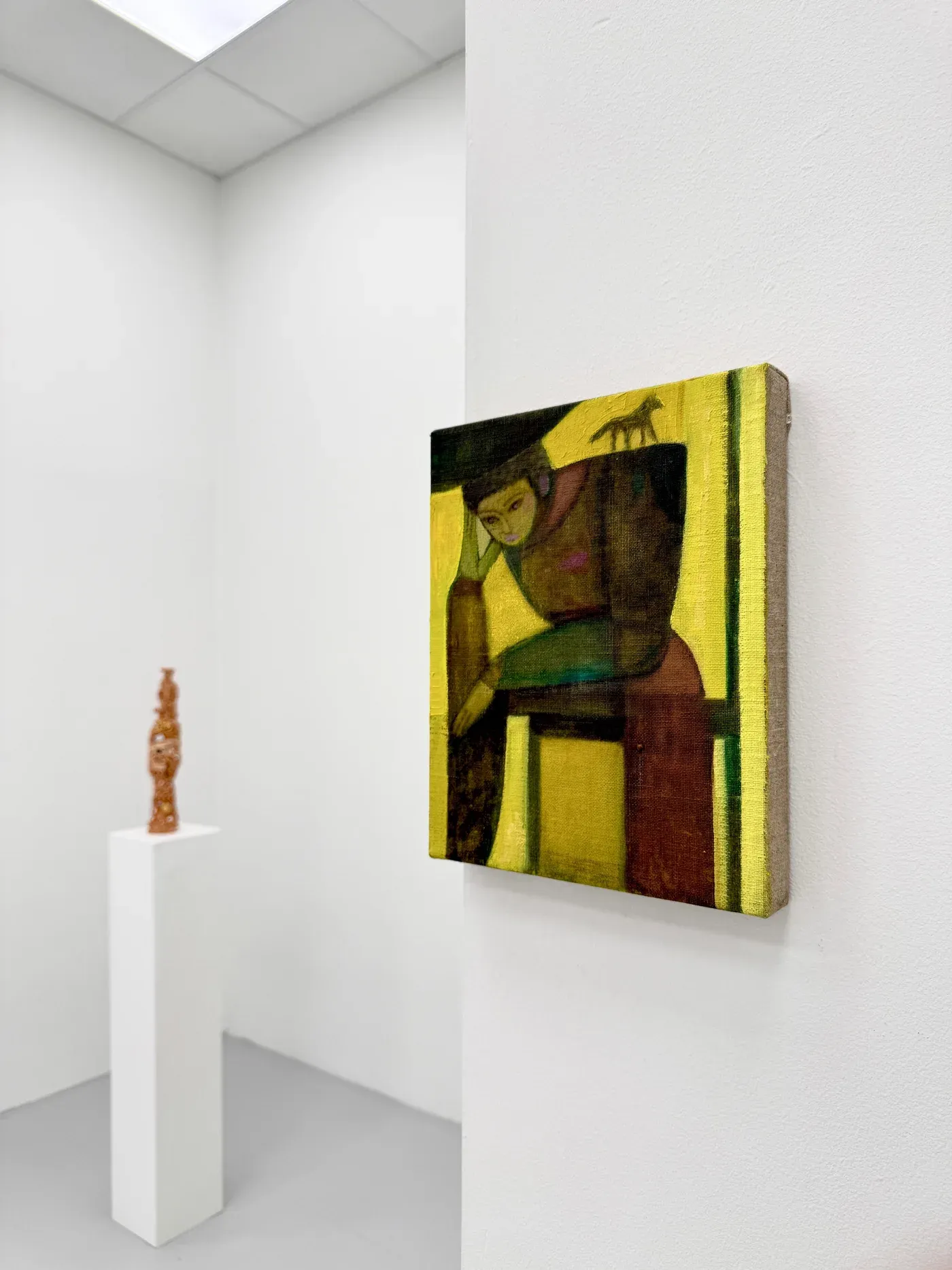 Close-up installation view showing Bob Geerts’ small figurative painting in warm yellow and brown tones beside a terracotta sculpture by Glenn Barkley on a white pedestal, at HAGD Contemporary, Aalborg, Denmark.painting-stoneware-duo