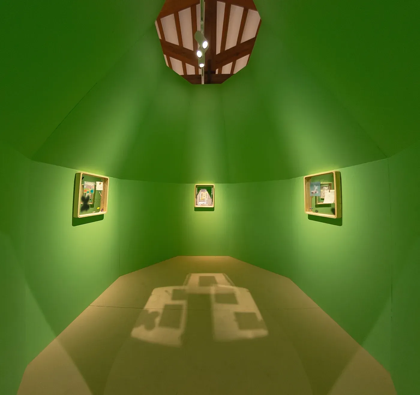 Green room installation with three framed works by Grip Face displayed on curved walls, softly lit to create an immersive environment