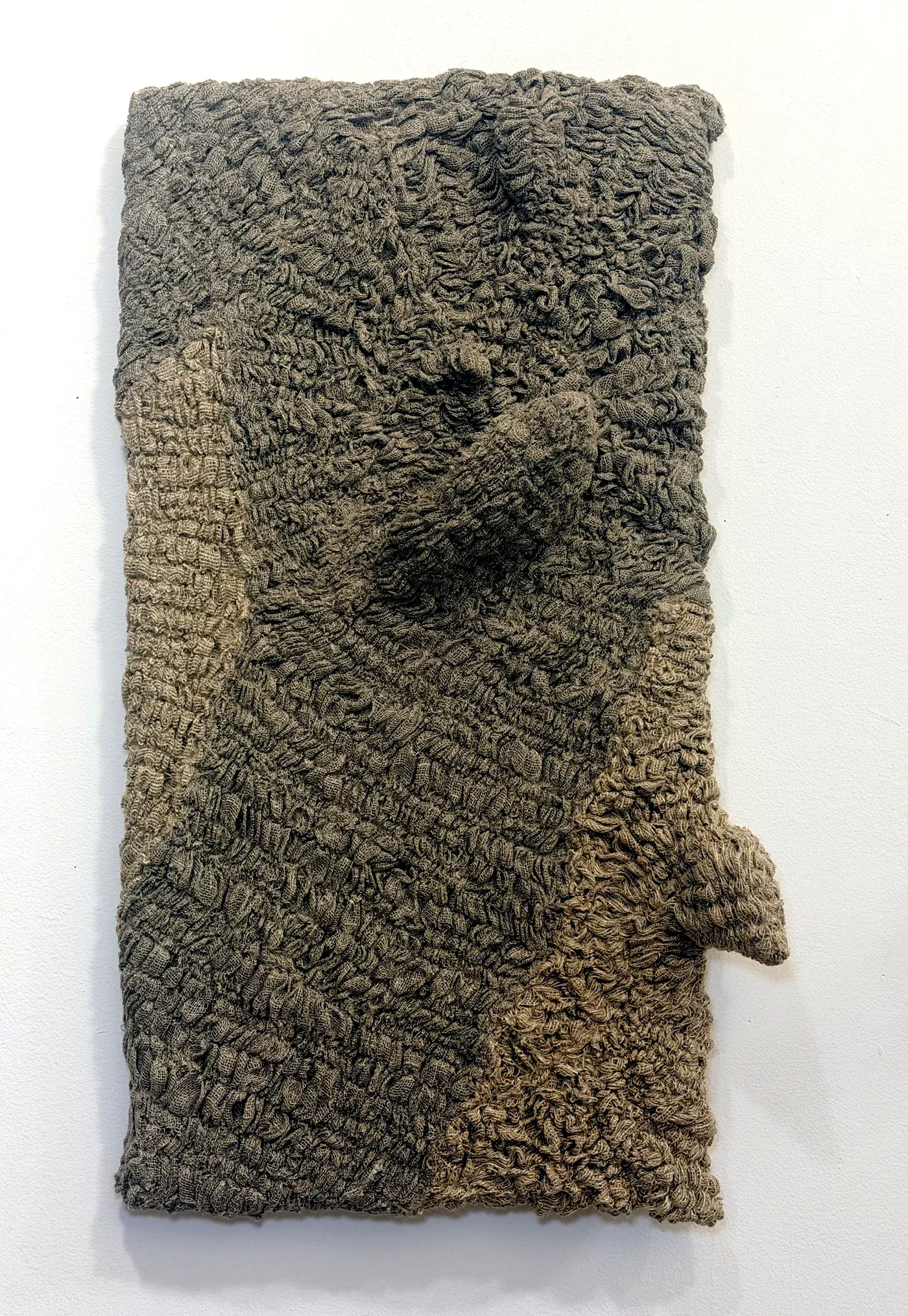 Yali Romagoza, Skin Panel #5 (2024), linen and thread on wood panel, textured fiber relief resembling skin or landscape patterns, photographed against a white gallery wall.