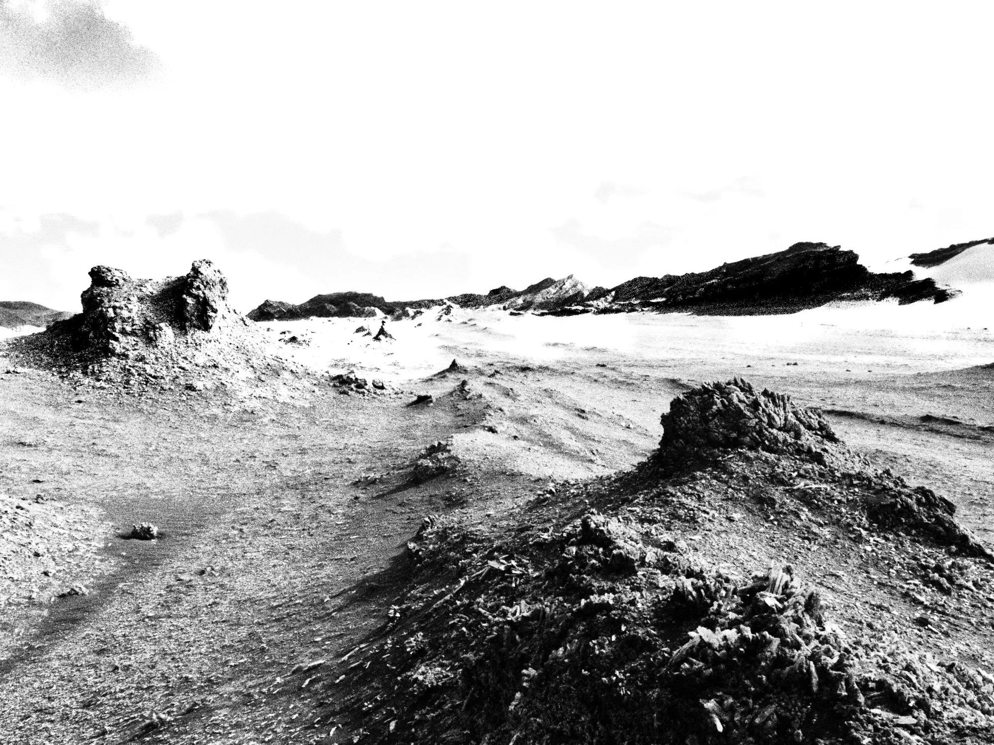 Black-and-white desert landscape photograph from Emergent Phenomenon by Nadine Karl, showing eroded terrain and rock formations.