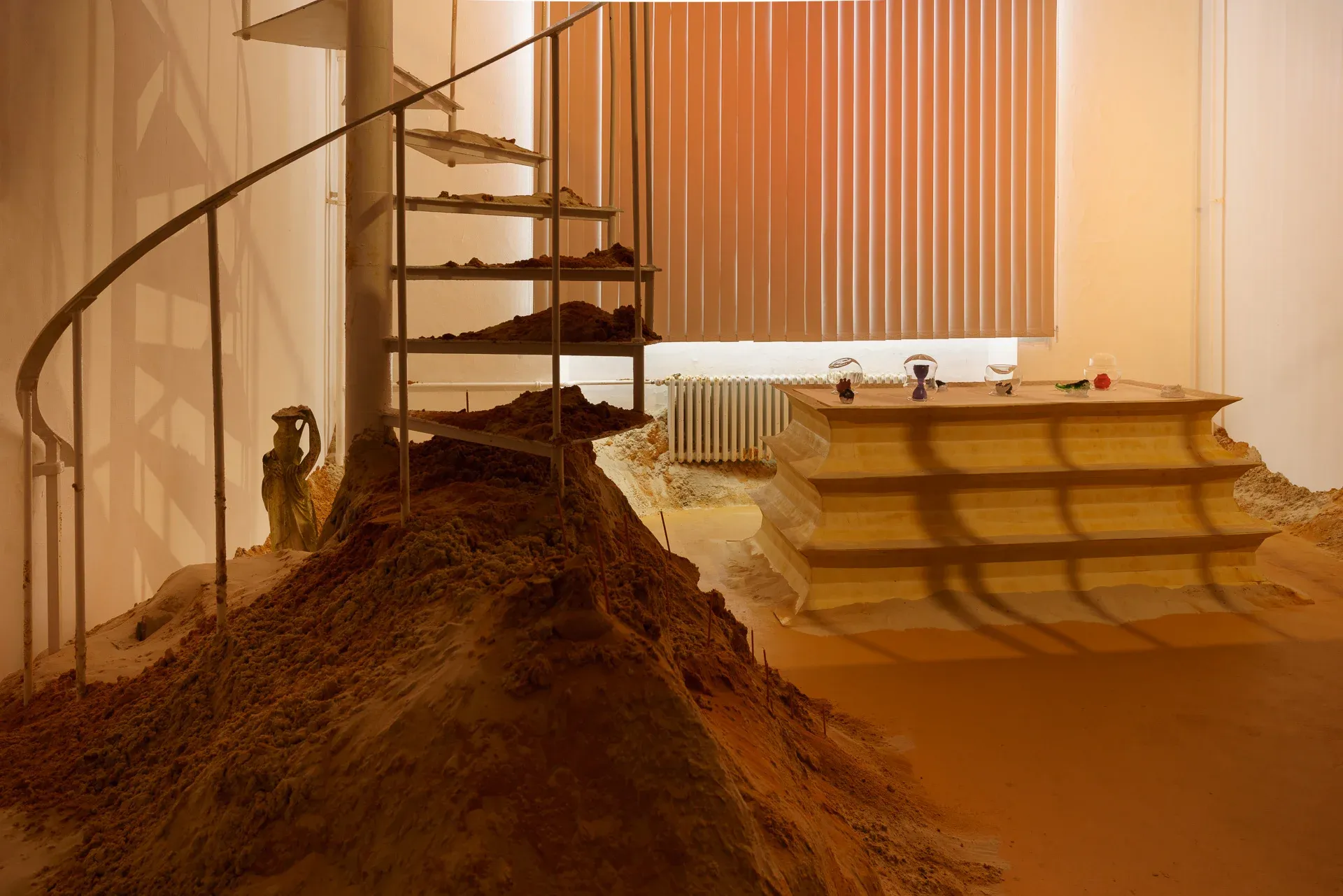 Installation view of Nadine Karl’s graduation work as far as I feel – about thoughts and throughs, featuring sand, architectural elements, and sculptural forms in an interior space.