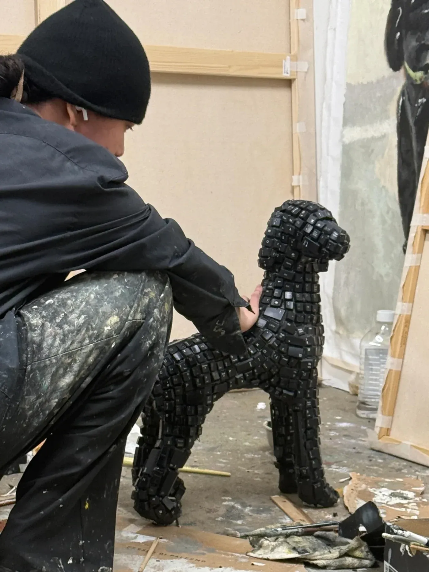 Yutaro Inagaki, Sculpture of a dog made from foam and layered black keyboard keys with the artist crouched beside it.