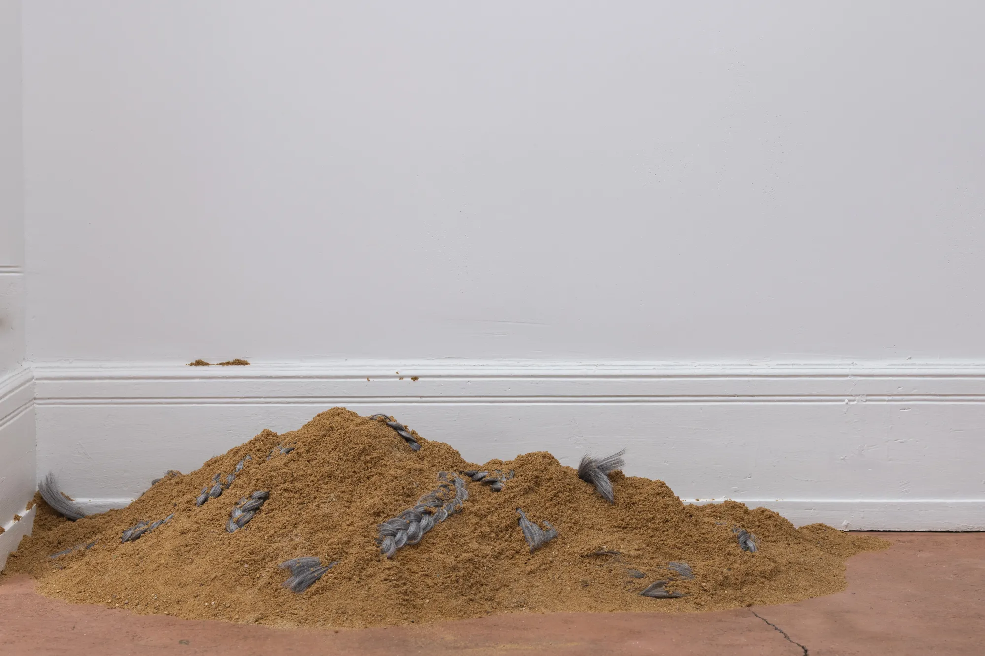 Installation view of After Unrast by Nadine Karl at Kunsthalle DĂĽsseldorf, showing a glass display with sculptural elements and a large black-and-white photographic work mounted on the wall.