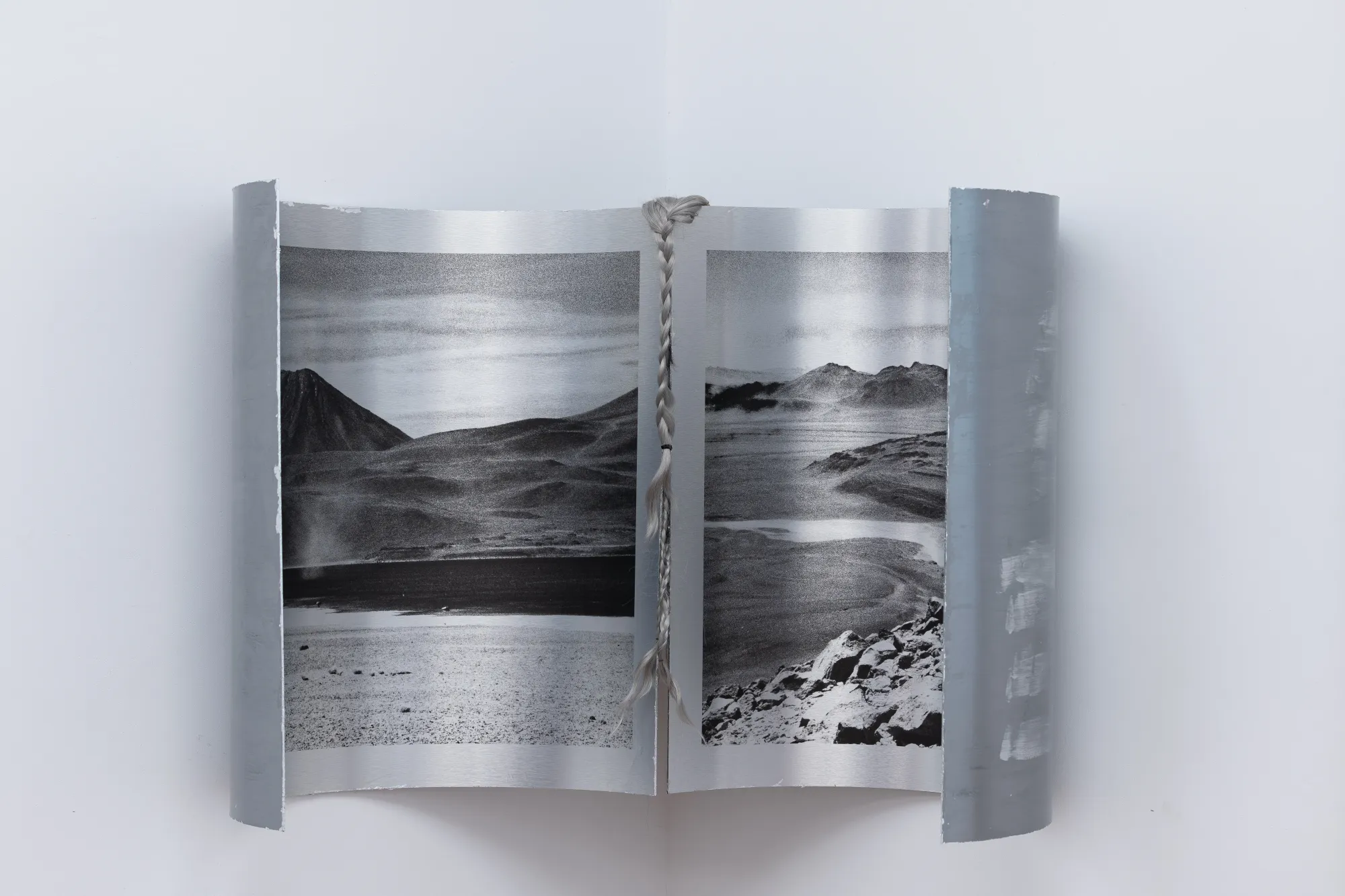 Wall-mounted photographic work by Nadine Karl in Epiphenomenon, showing black-and-white desert landscapes presented in curved metal frames.