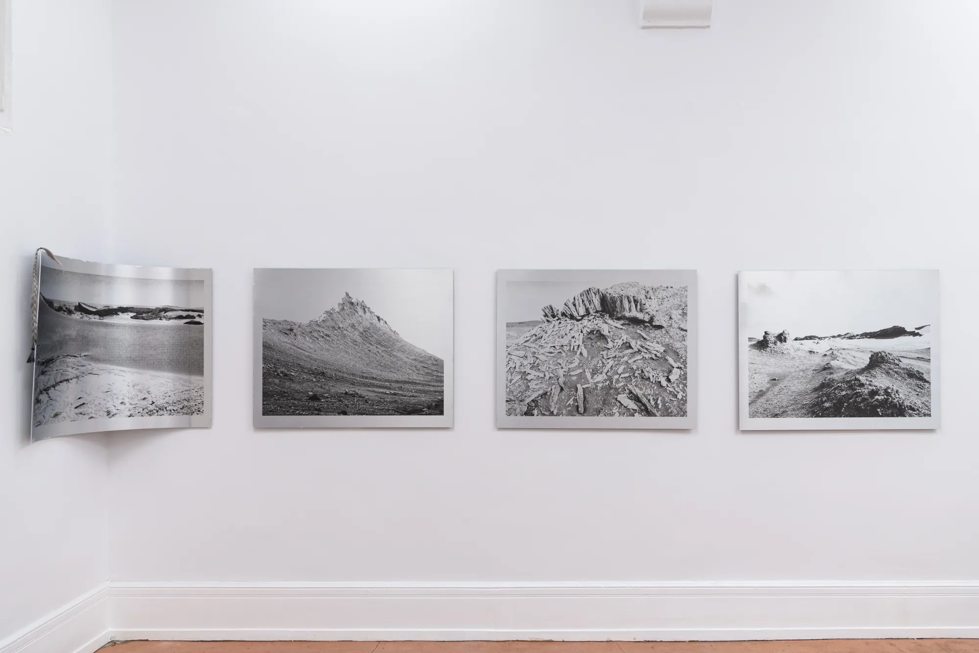 Installation view of Nadine Karl’s photographic series in Epiphenomenon, with multiple black-and-white landscape photographs aligned on a white wall.