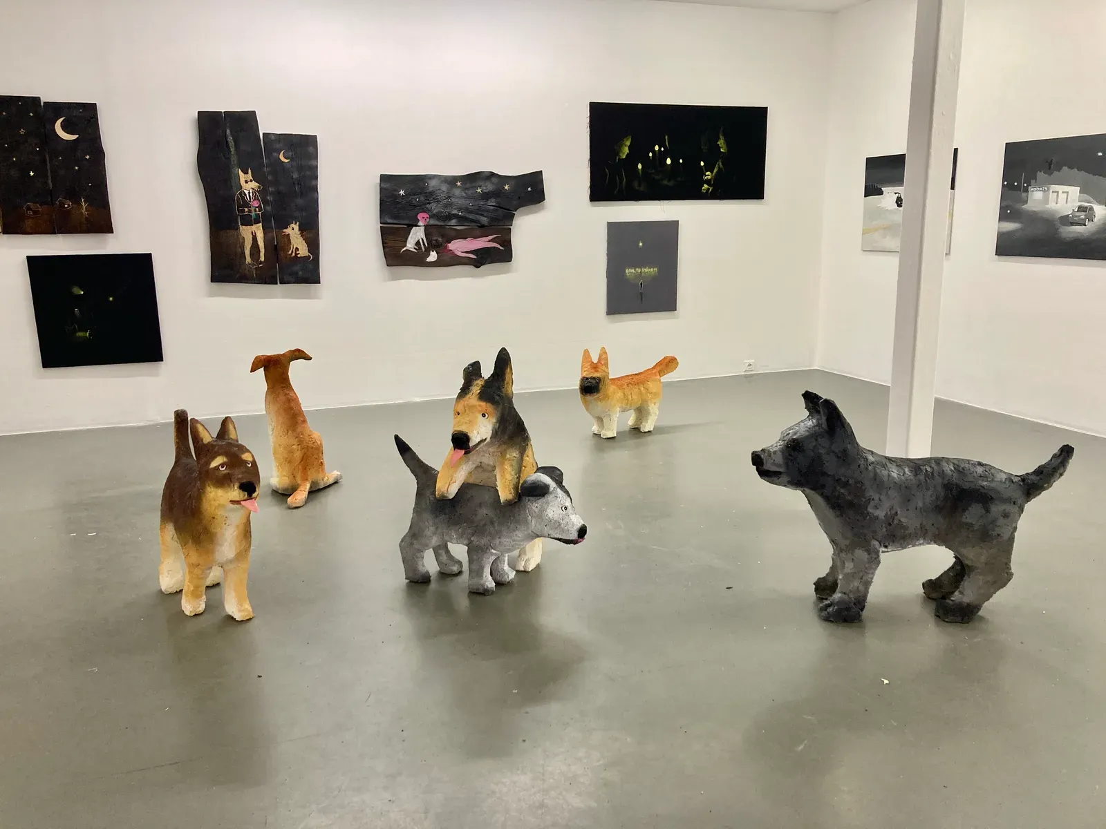 Ivan Volkov, exhibition view, with sculptures and wall pieces, dogs are playing around