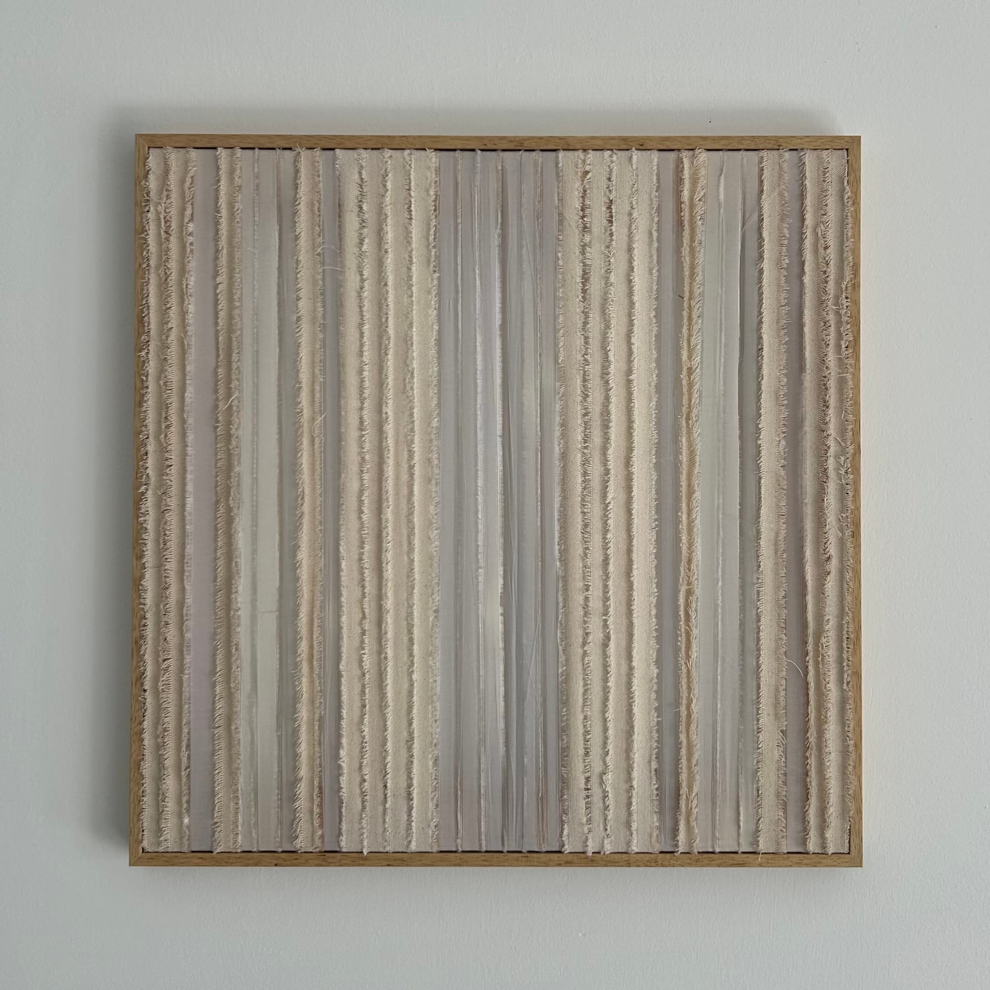 A square framed textile work composed of vertical bands of canvas fabric and polyester, alternating between sheer and dense textures that create a rhythmic, softly striated surface.
