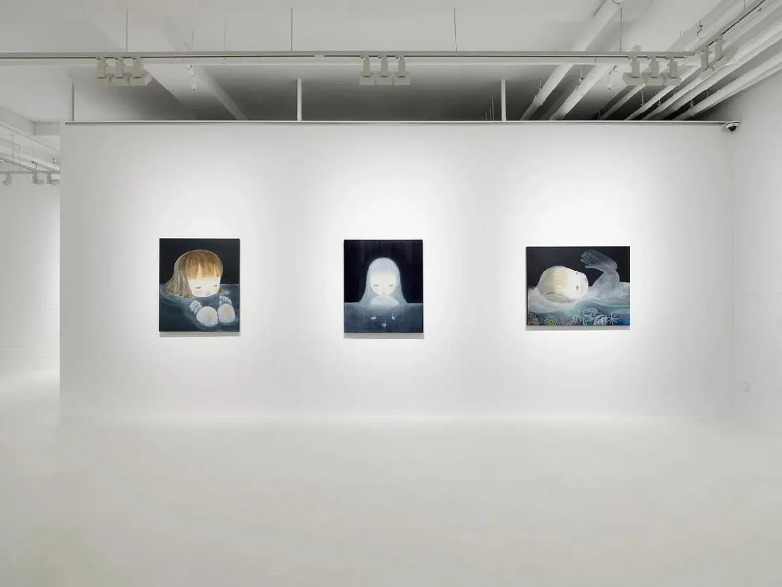 Installation view of three paintings by Ruo-Hsin Wu displayed in a minimalist gallery space at Eligere Gallery, featuring pale figurative works set against dark backgrounds.