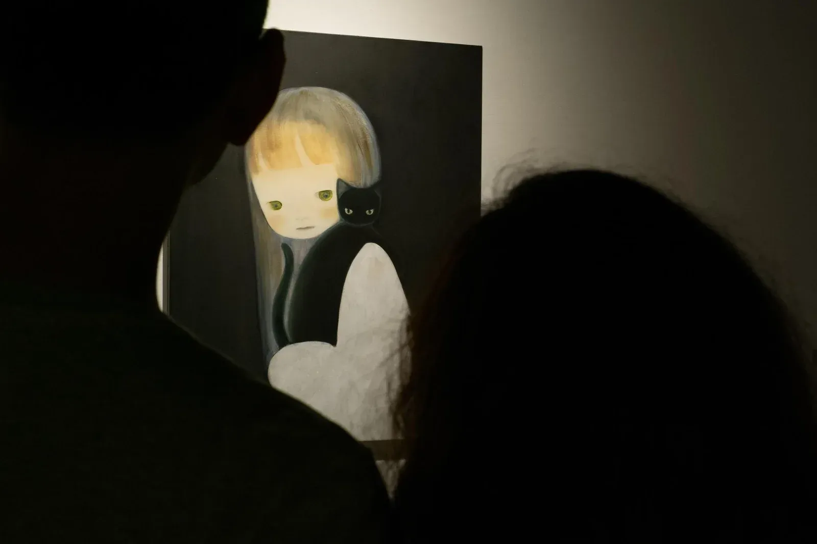Installation view of a painting by Ruo-Hsin Wu seen through silhouetted viewers at Srisasanti Gallery, featuring a pale figurative figure against a dark background.