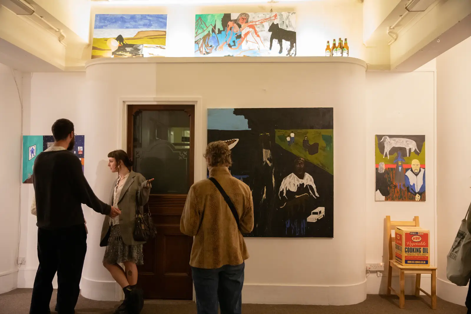 Visitors standing close to a Paes painting during an exhibition, engaged in discussion.