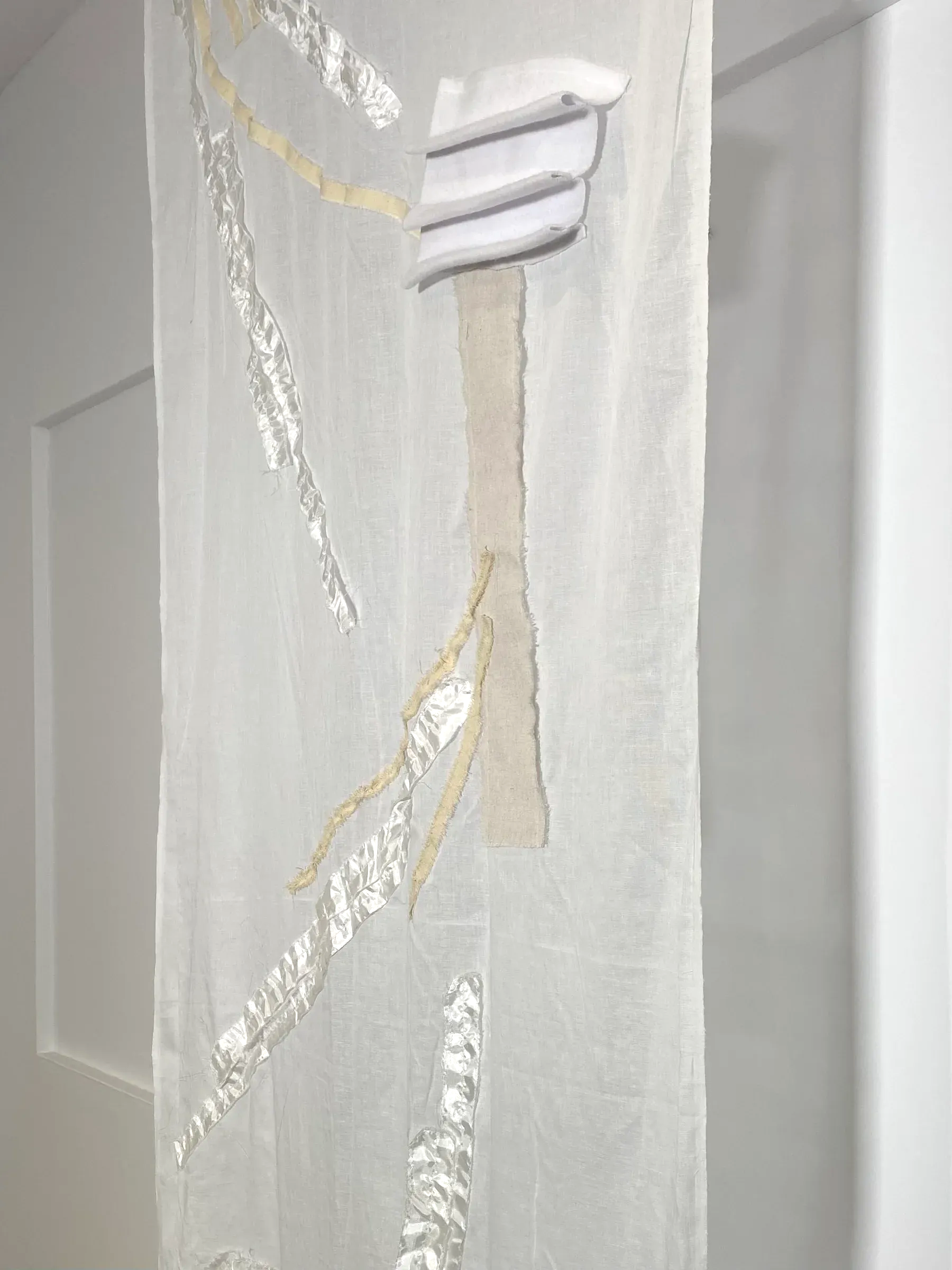 detail view of a translucent textile surface showing stitched paths of cheesecloth, polyester and linen, highlighting texture, seams and light variation.