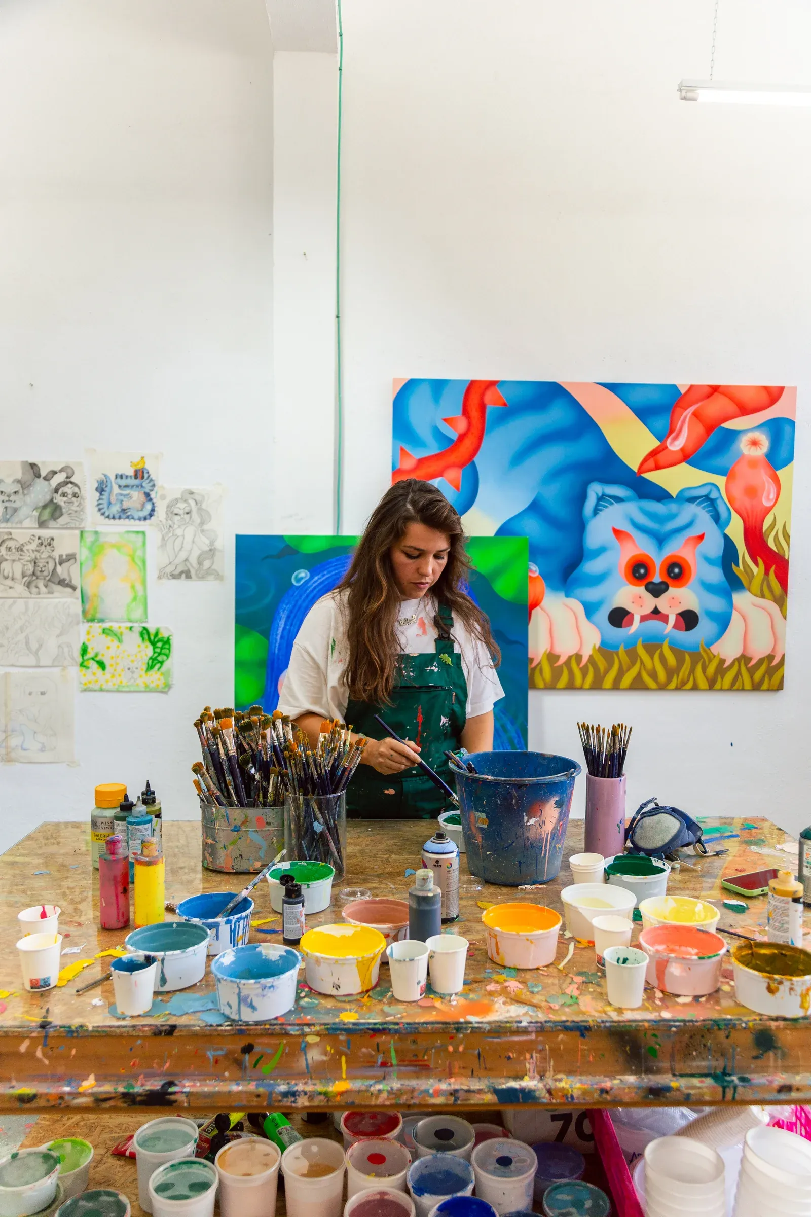 Fátima de Juan, Close-up of the artist painting facial details on a stylized figurative canvas in her studio.