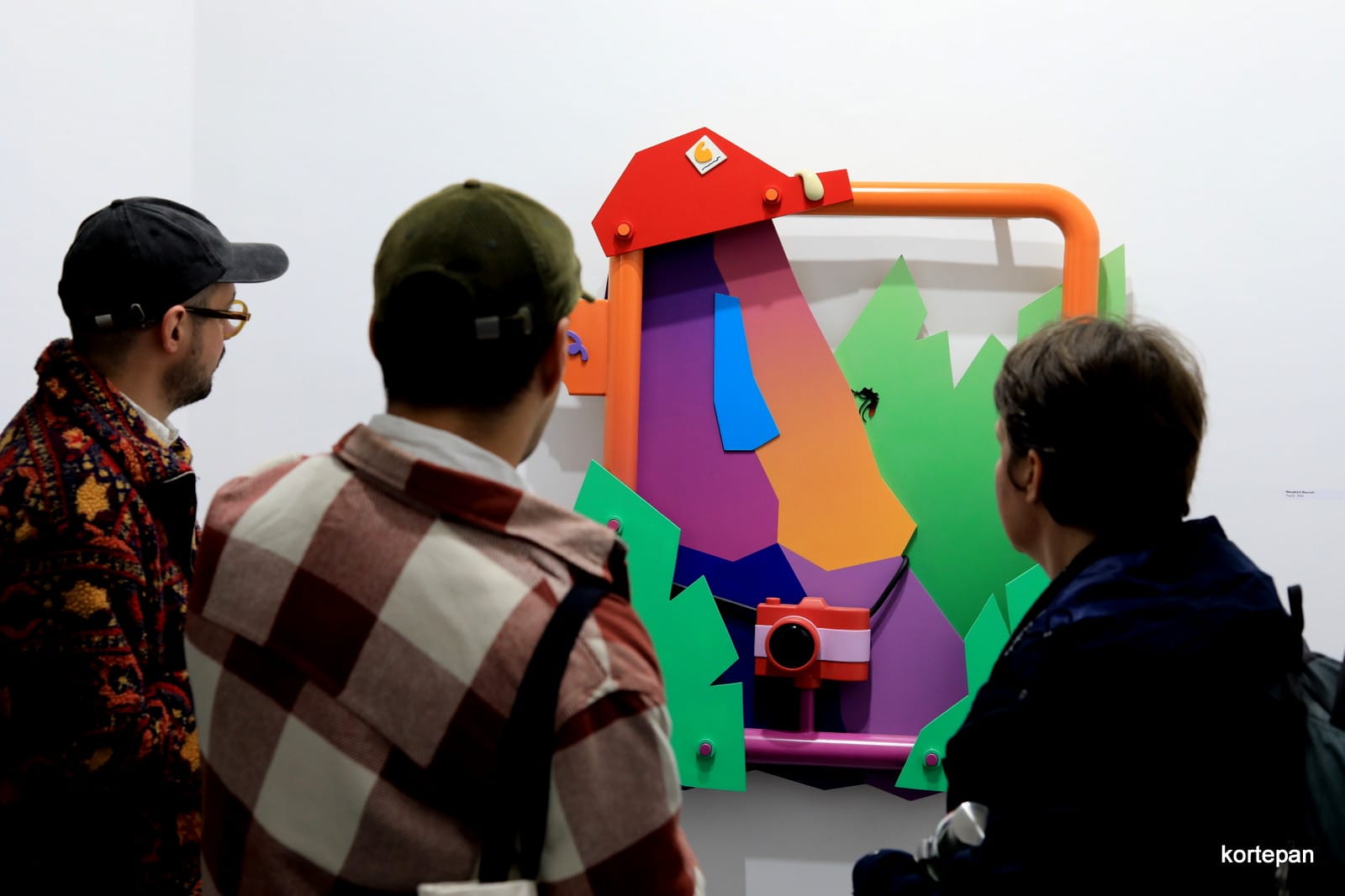 Marcell Daniel Menyhart , exhibition visitor looking at a colorfull wallpiece sculpture