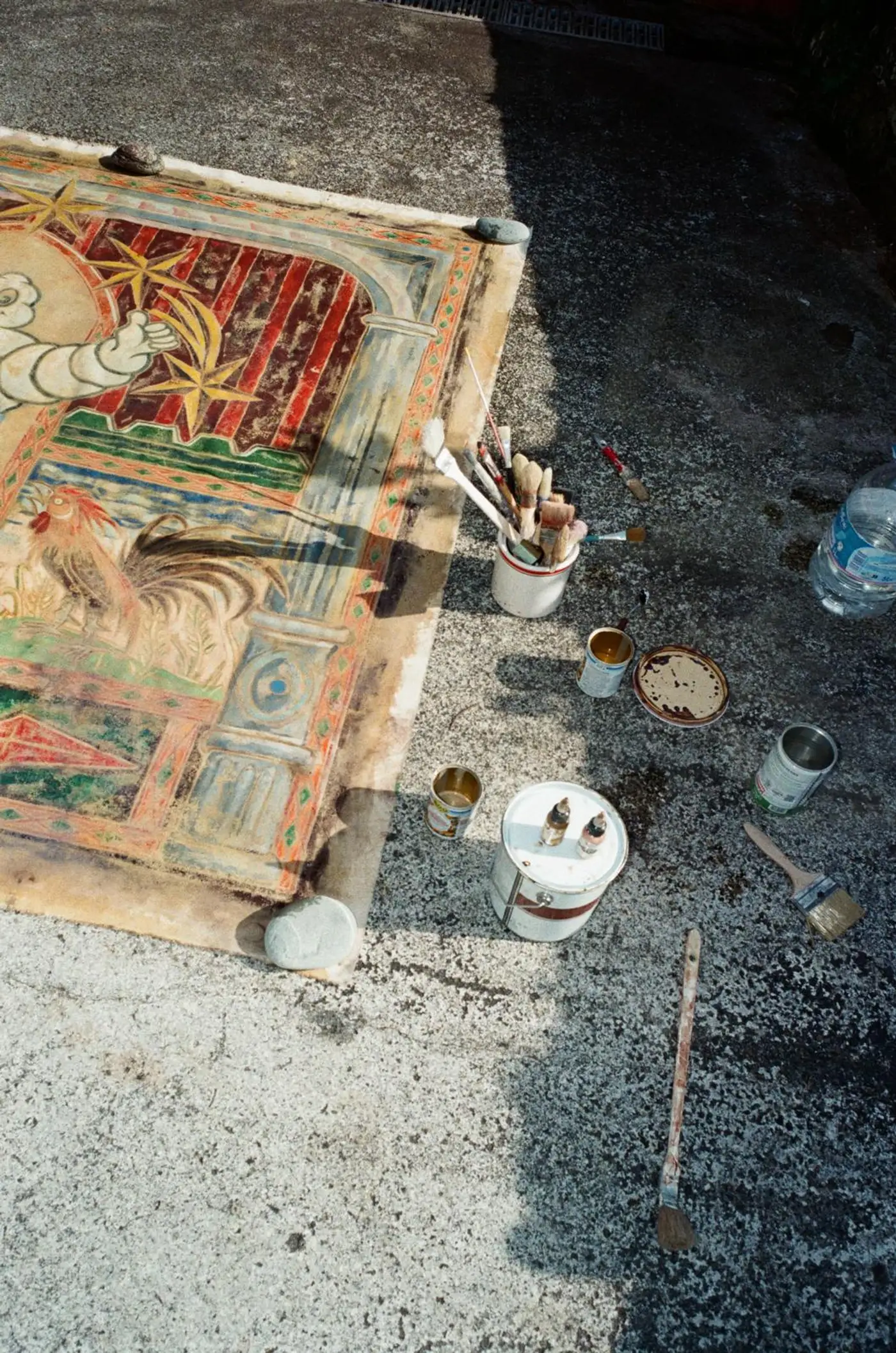 Ruben Einsmann working outdoors on a large painting laid on the ground during the painting process.