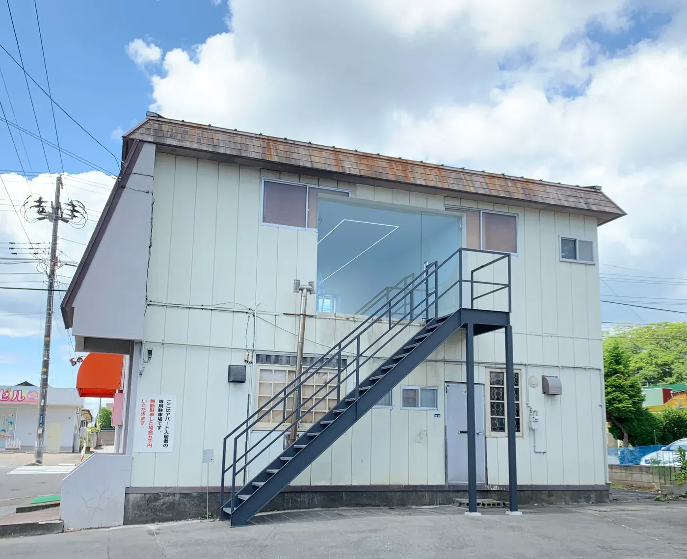 Front façade view of 目 [mé]’s installation space (2020) at Towada Art Center, featuring a large rectangular opening revealing a luminous interior within an existing building structure
