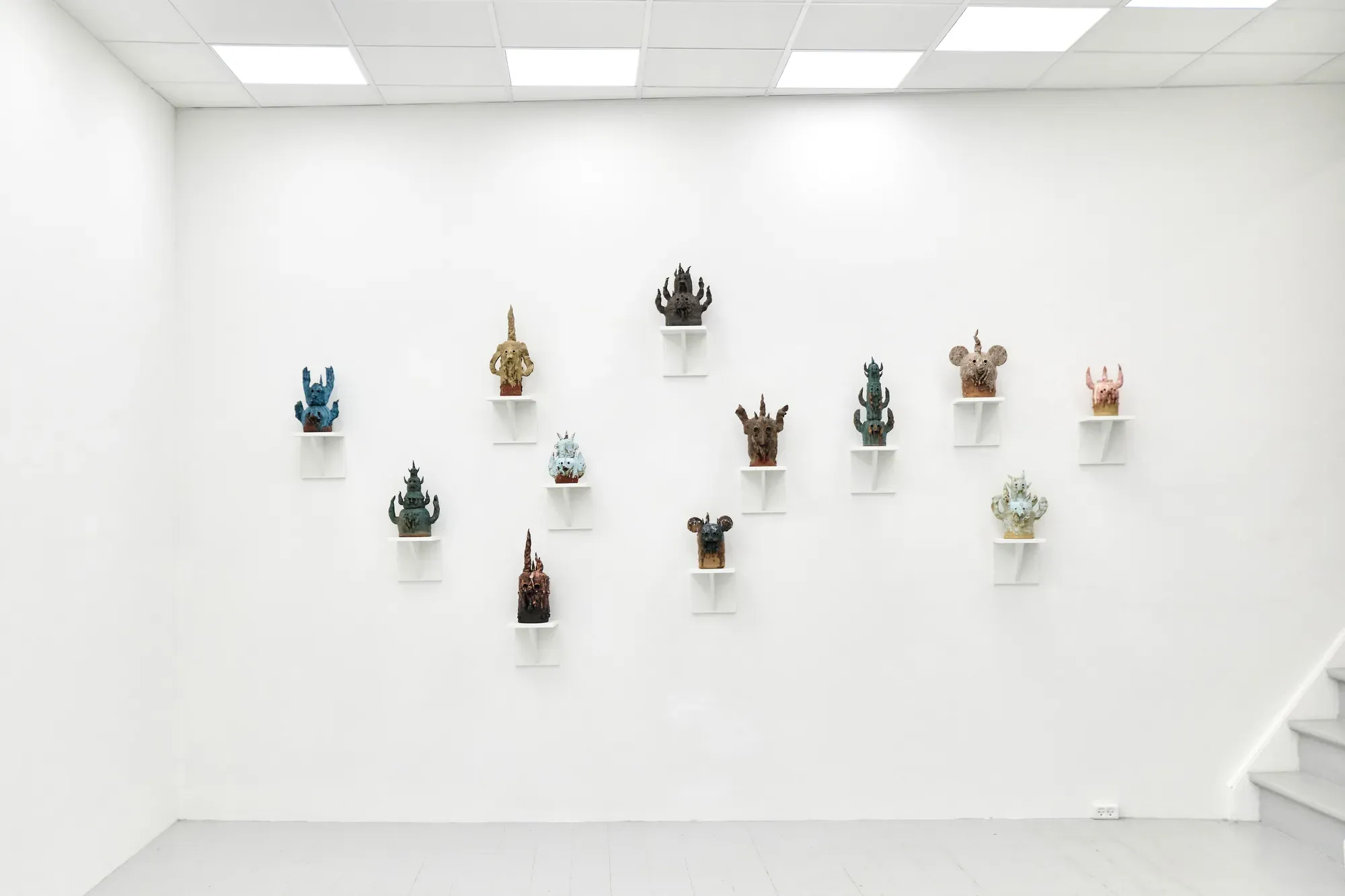 Installation view of Mother of Many by Michael Kærgaard at HAGD Contemporary, Aalborg, showing multiple stoneware sculptures mounted on individual wall shelves in a spatial grid.