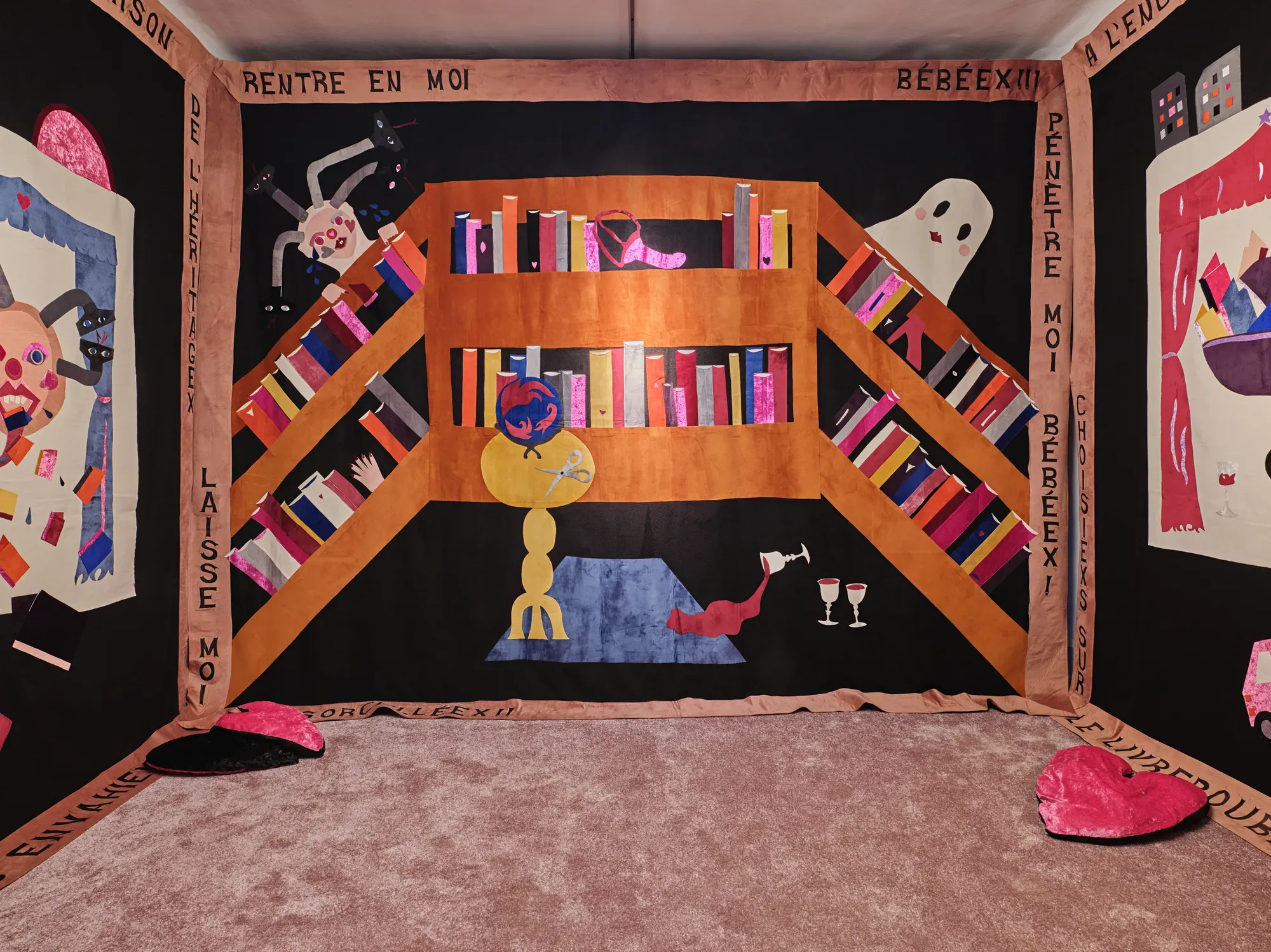 Large textile wall installation by Cécile Bouffard depicting a stylized interior scene with bookshelves, figures and symbolic objects in the exhibition “Stitches: A Haunted House and Other Ghost Stories”, Villa Bernasconi, 2026.