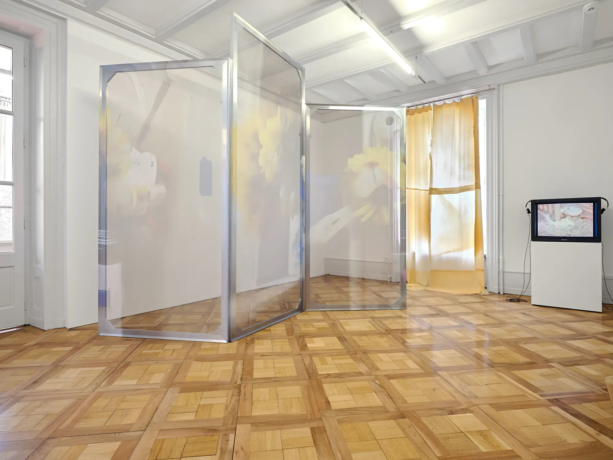 Installation by Louise Hervé and Chloé Maillet with translucent folding panels and video monitor in the exhibition “Stitches: A Haunted House and Other Ghost Stories” at Villa Bernasconi, 2026