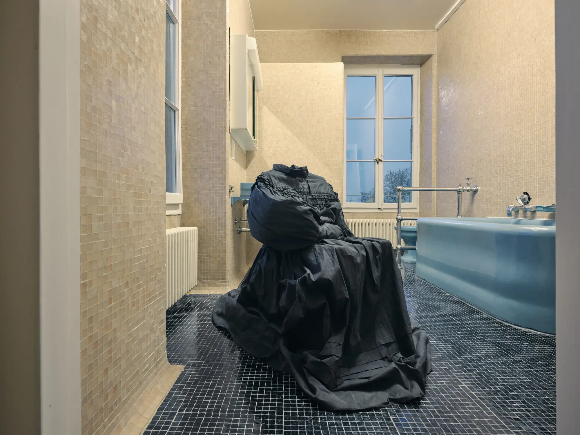 Marie Matusz textile installation with a black garment-like form placed in a bathroom setting beside a bathtub in the exhibition “Stitches: A Haunted House and Other Ghost Stories” at Villa Bernasconi, 2026.