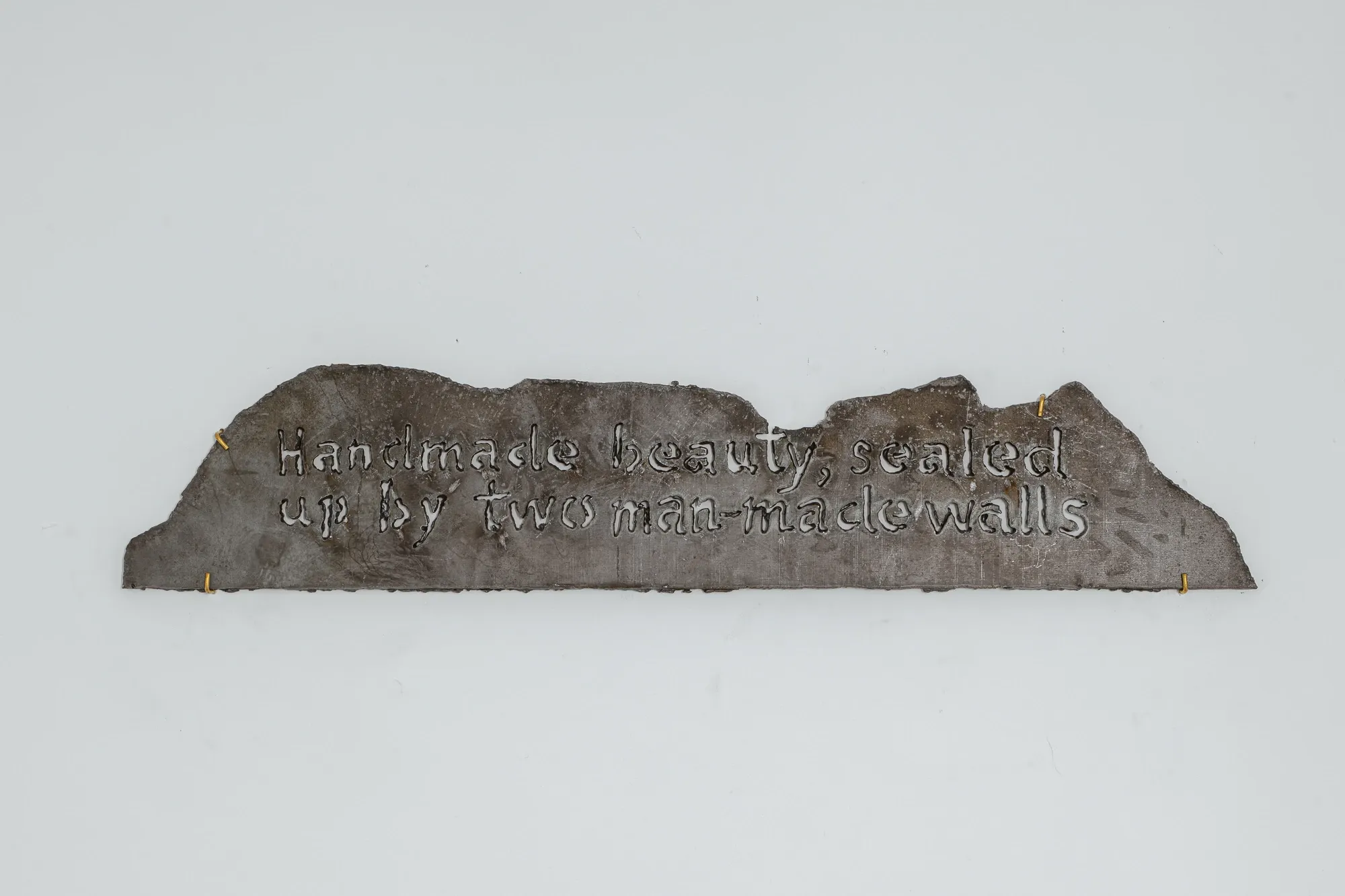 Liudvikas Kesminas letters in a piece of metal, man made beauty, scaled up by two man made walls written , cut out