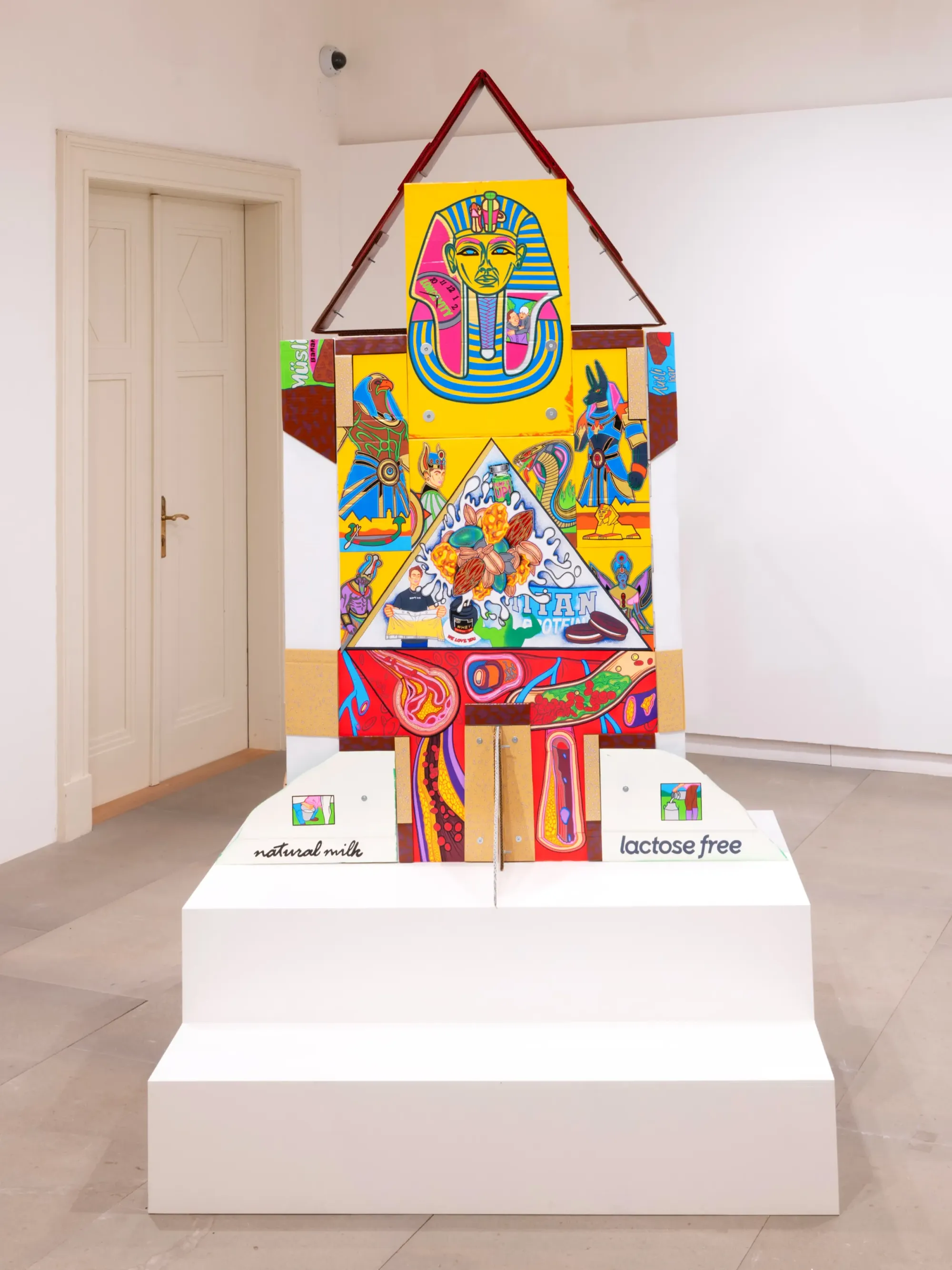 Frontal view of colorful cardboard temple installation with Egyptian motifs, anatomical imagery and graphic patterns, Daniela Ponomarevová