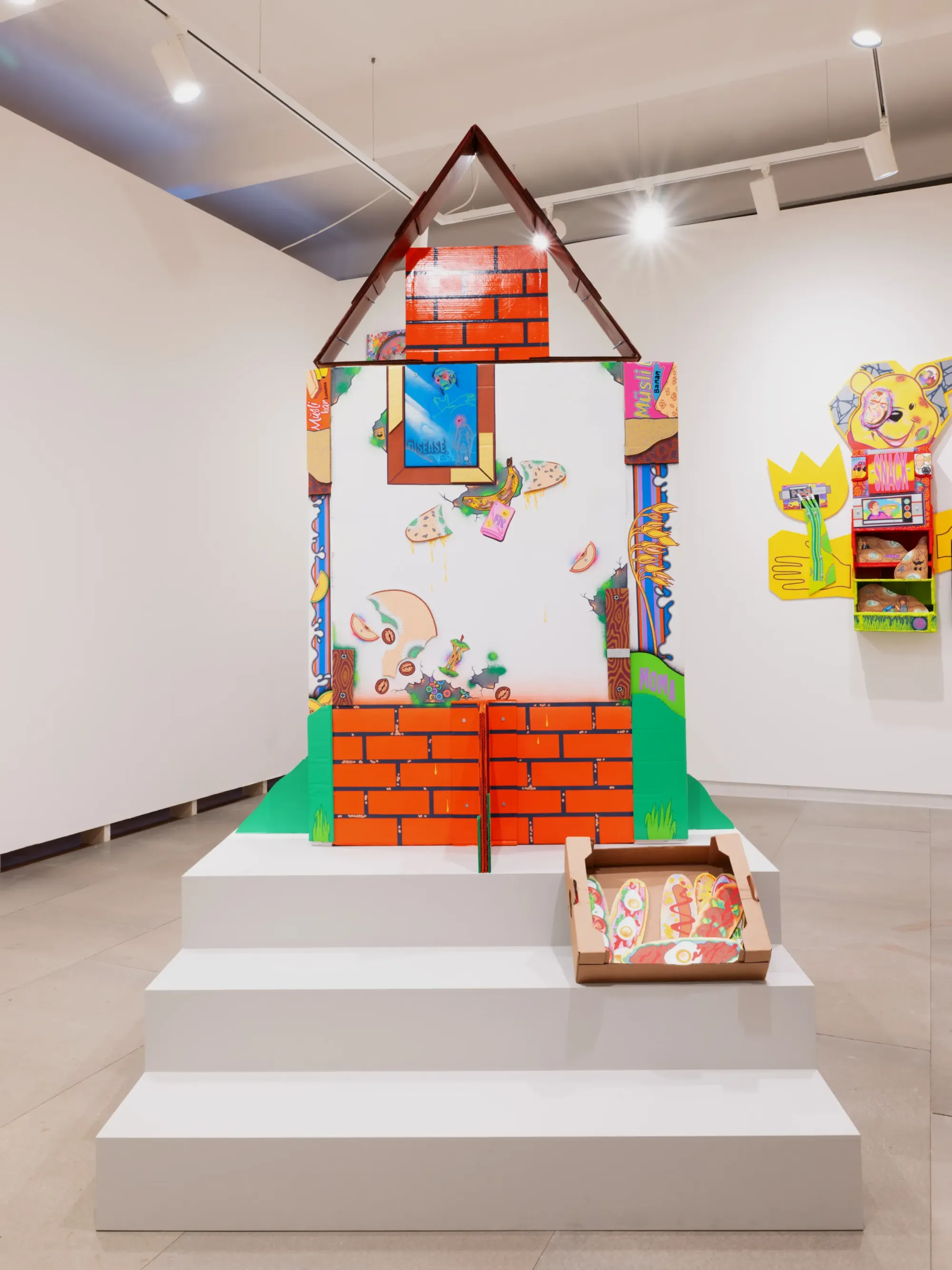 Back view of colorful cardboard temple installation with painted brick pattern and graphic elements, Daniela Ponomarevová