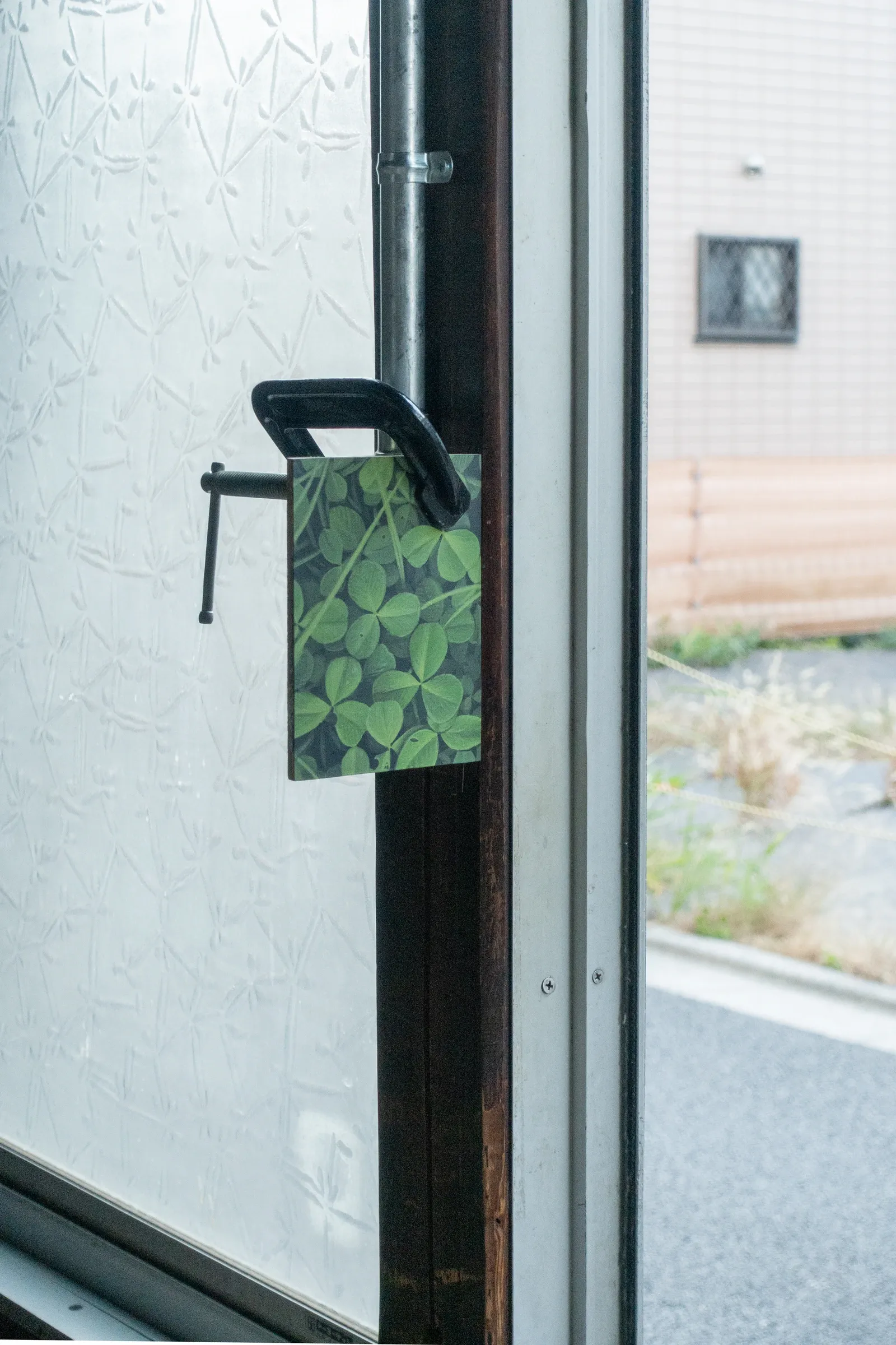 Detail of artwork by Paul Riedmüller titled Giftige Finger installed on a door handle in Studio Gross Tokio, combining everyday object with printed image of green leaves