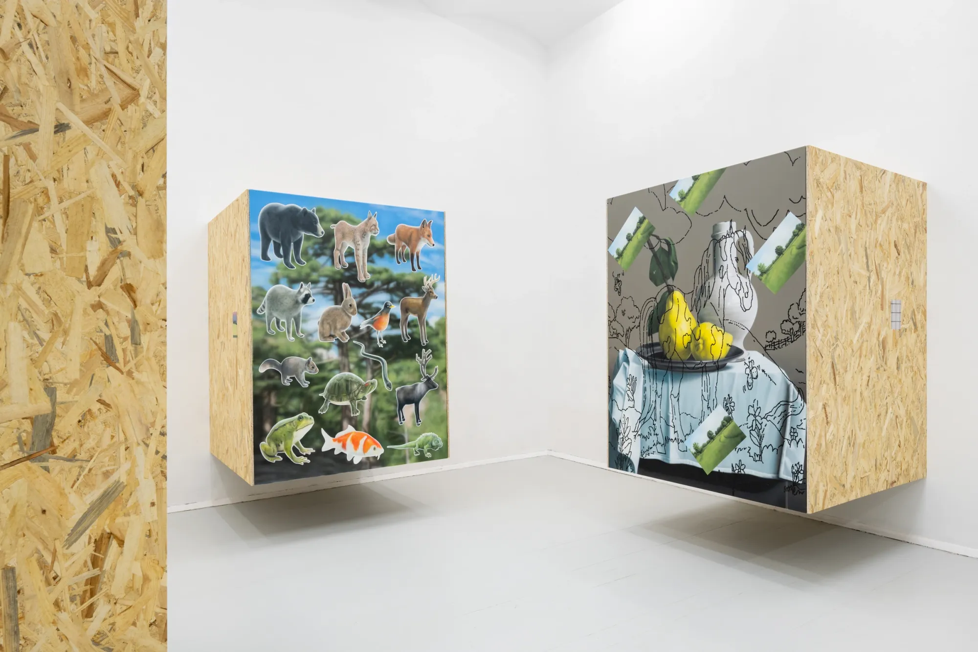 Installation view of Paul Riedmüller at Koenig 2 Vienna showing suspended box structures with printed imagery and painted surfaces in a white gallery space