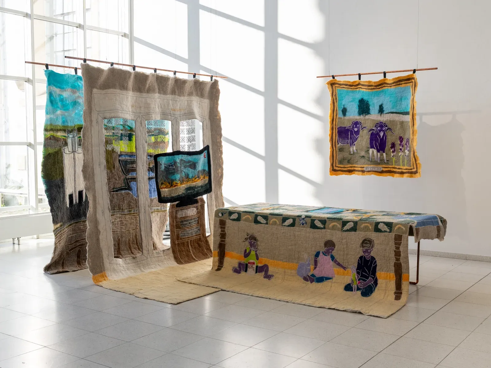 Pierre-Yves Delannoy, Pendant que les champs brûlent (2025), large felt textile installation with hanging landscape scenes and domestic interior imagery, contemporary textile art environment exploring memory, rural landscapes and everyday life.