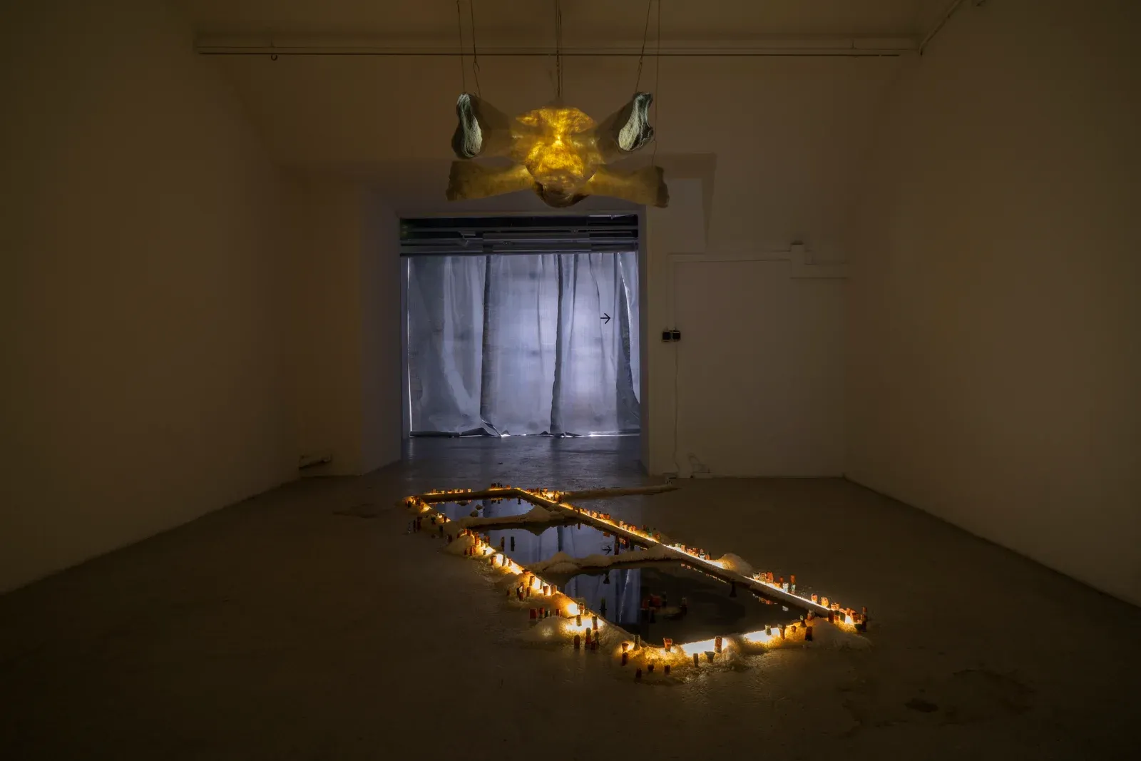 Pierre-Yves Delannoy, I felt your fleece in the tidal valley (2023), atmospheric installation with illuminated sculptural elements surrounding reflective surfaces in a darkened gallery space.