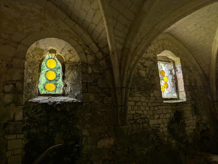 Romane Charlot, GRAINS DE VERRE and ROUET DE VERRE, 2025. Activatable stained glass works installed in stone window openings, composed of glass, steel and tin with circular yellow glass elements. Photo © Simon Desmura.