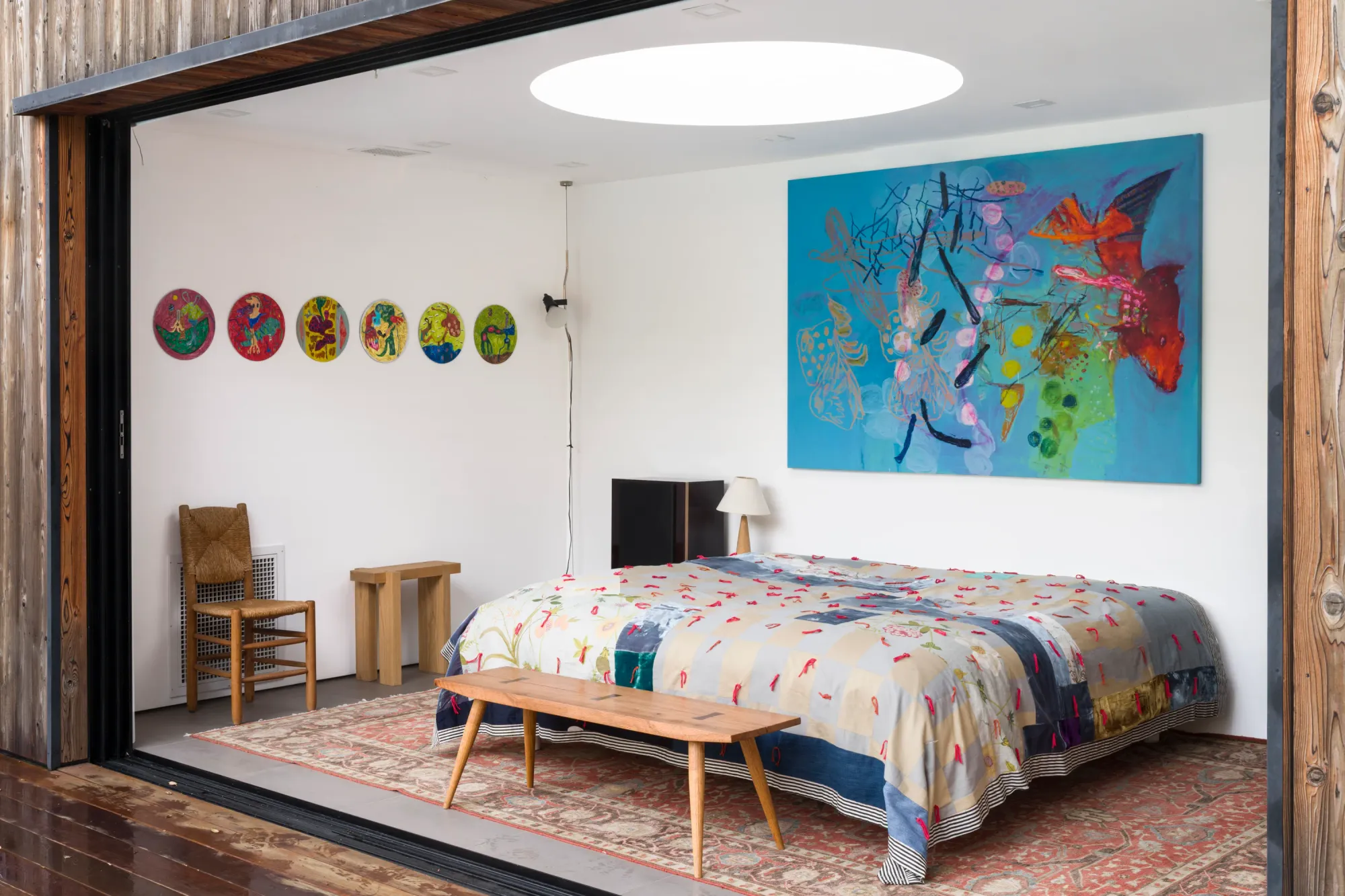 Installation view of Dinner Table at Simchowitz showing paintings by Andrey Samarin and circular works by Lera Derkach displayed in a bedroom-like interior installation.